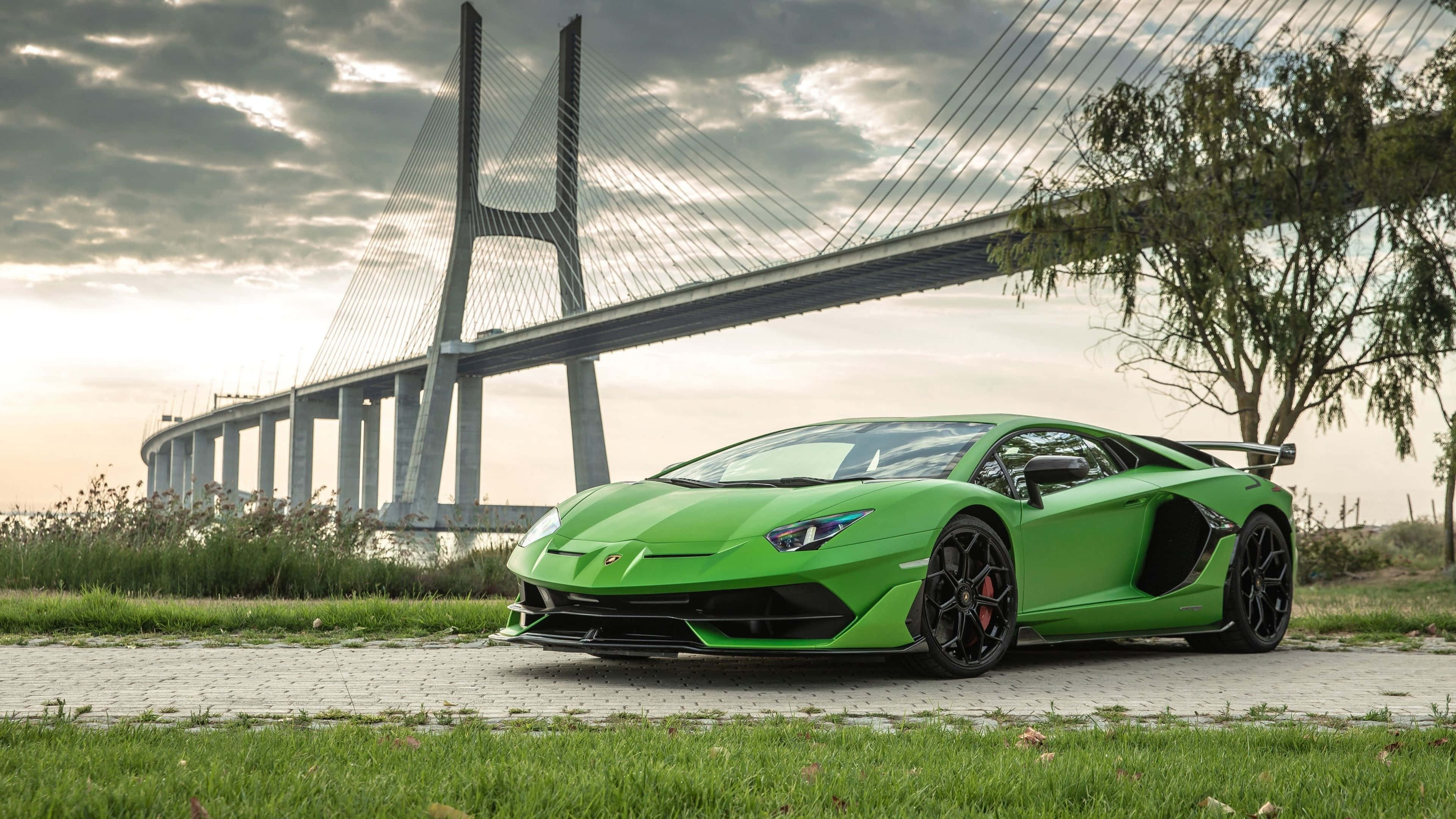 林寶堅尼 4K 桌布 壁紙 — 一架鮮綠色林寶堅尼Aventador SVJ停泊在鋪砌小徑上，背後一座巨大的斜拉橋在陰天下若隱若現。