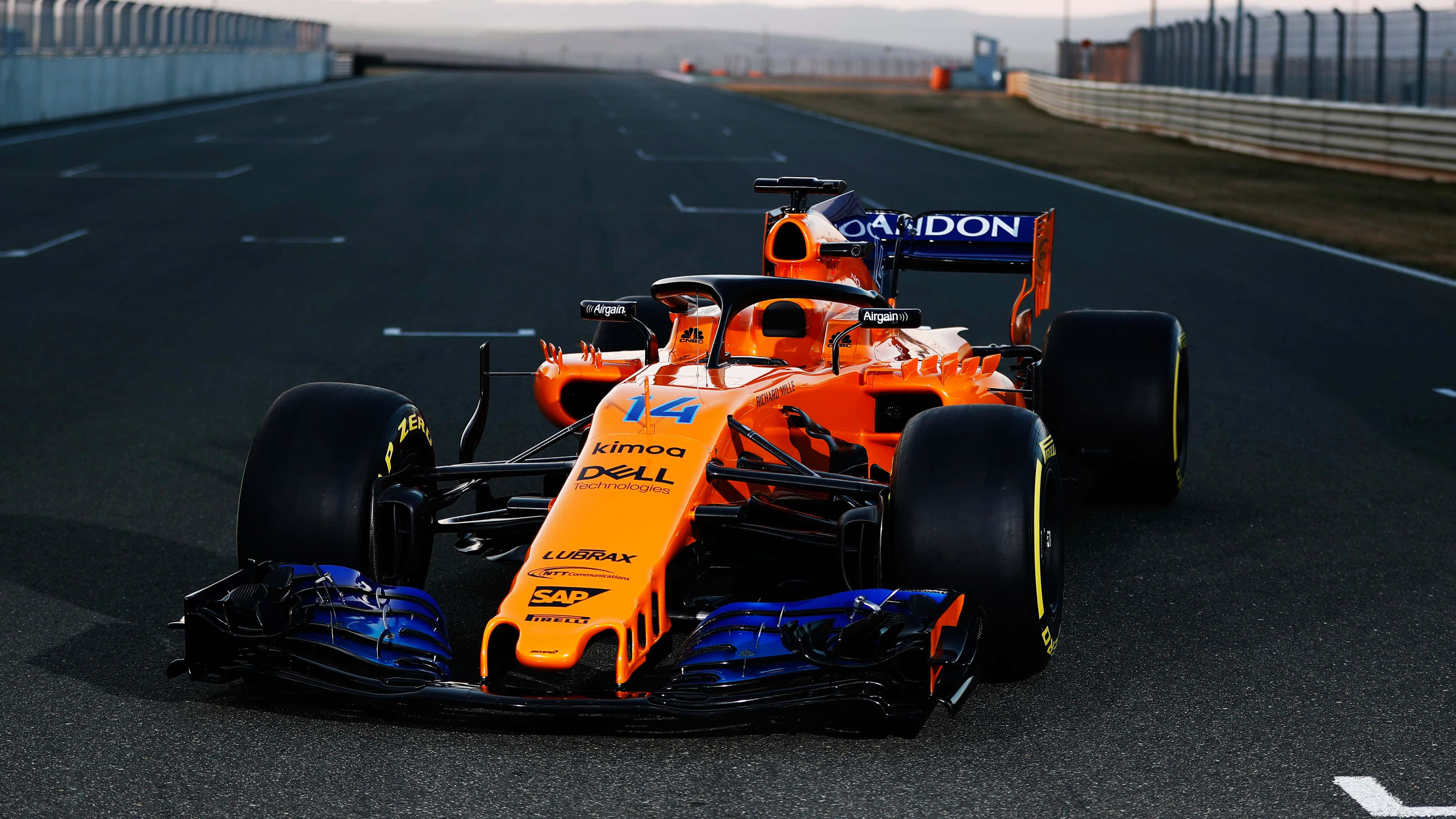 F1 2019 桌布 壁紙 — 一架鮮豔橙色和藍色的 Formula 1 賽車，編號 14，在晴朗天空下高速駛過賽道。