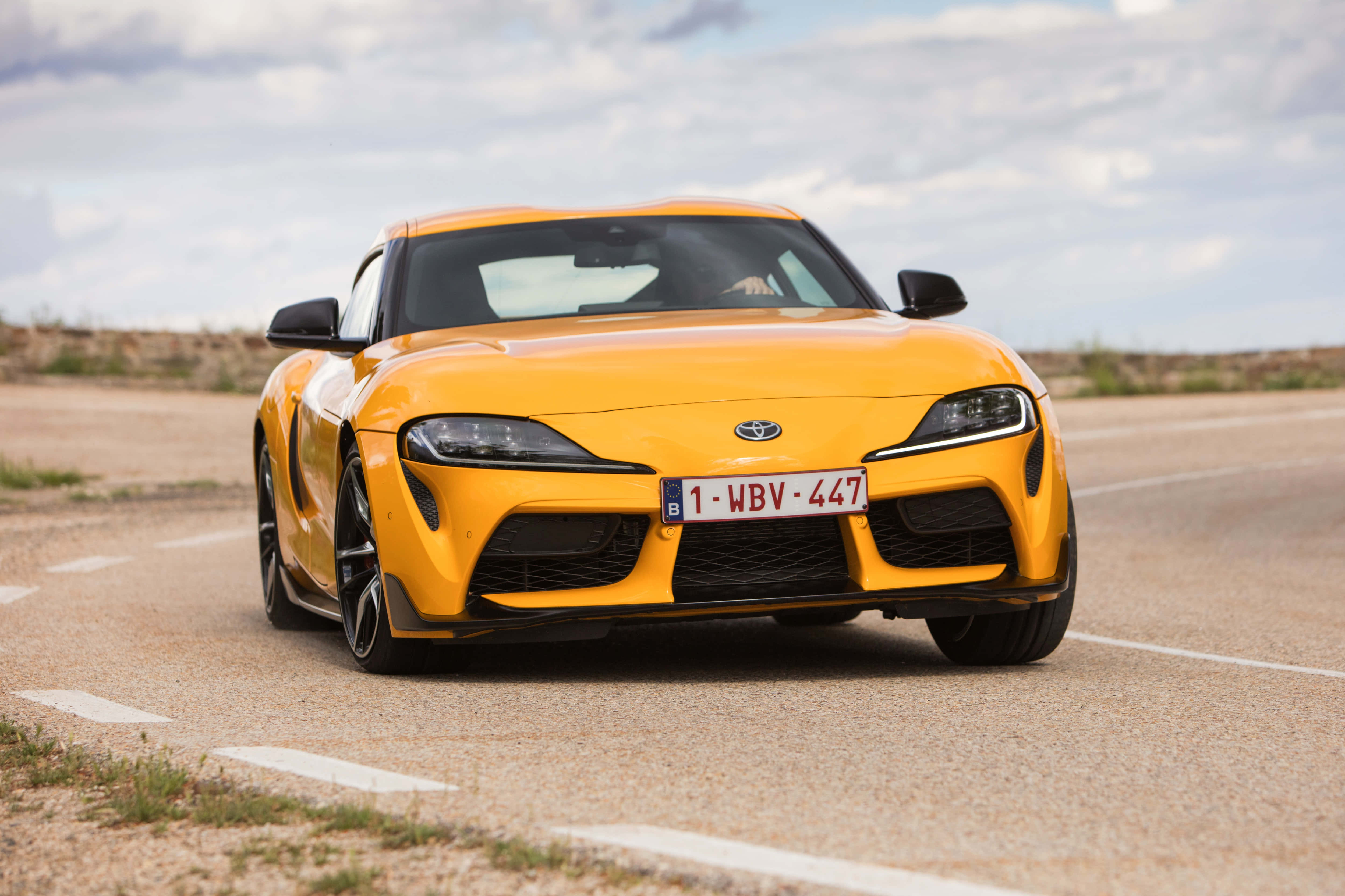Supra 桌布 壁紙 — 一架鮮黃色豐田Supra跑車停泊在沙漠公路上，天空多雲。