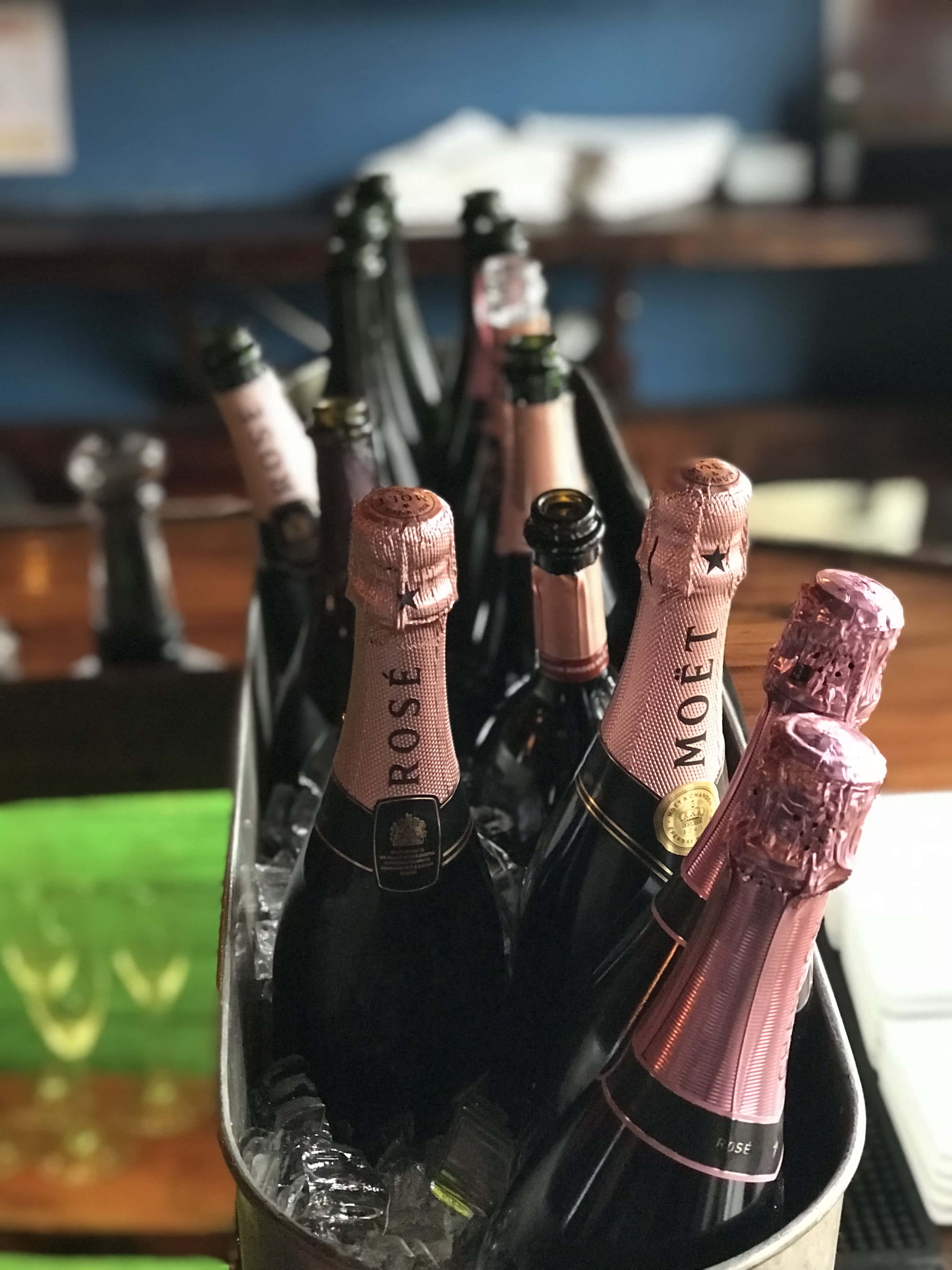 Pink Champagne 桌布 壁紙 — 一桶冰鎮 Moët & Chandon Rosé 香檳酒瓶放在酒吧枱上的冰塊中。