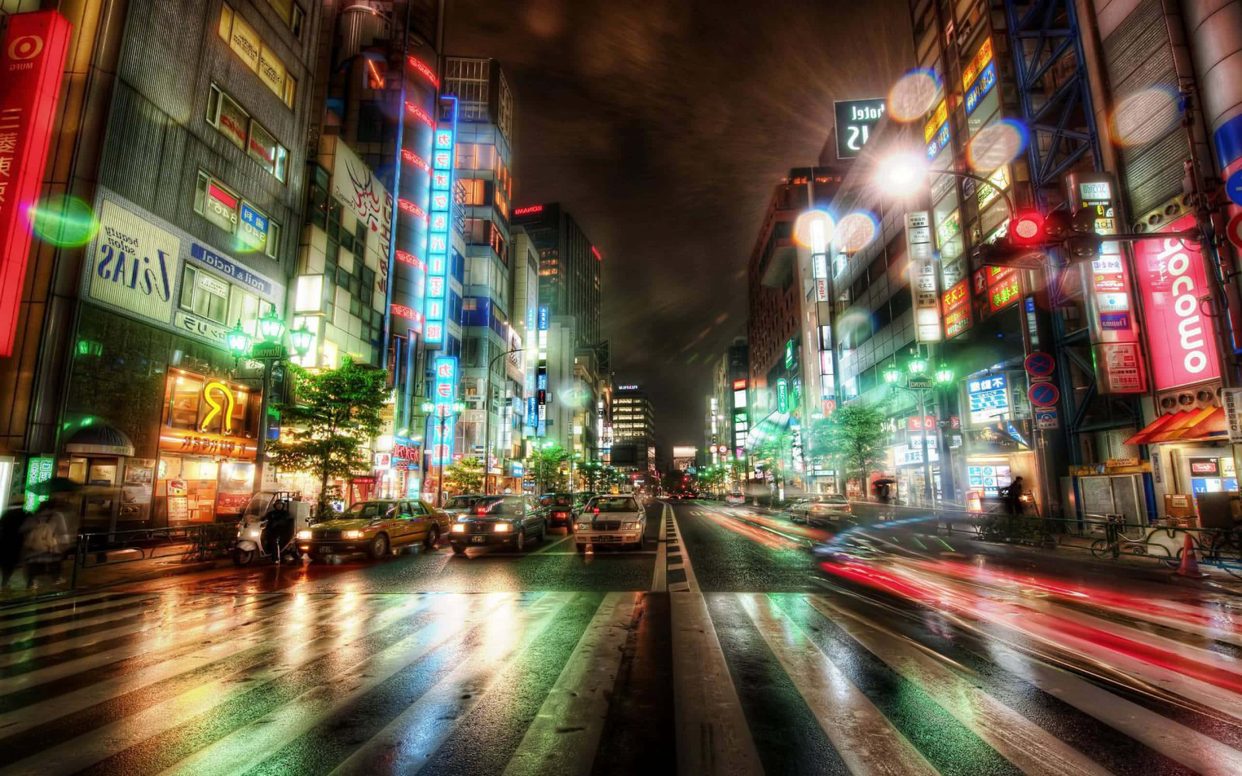 城市景觀 桌布 壁紙 — 一條充滿活力的東京霓虹燈街道夜景，車燈在濕漉漉的路面上留下長長的光影。