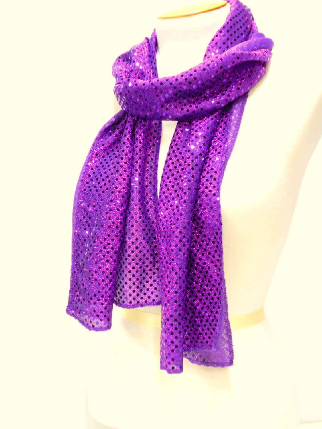 Purple Scarf 桌布 壁紙 — 一條充滿活力的紫色亮片圍巾，優雅地披在人體模型半身像上，背景是柔和的奶油色。