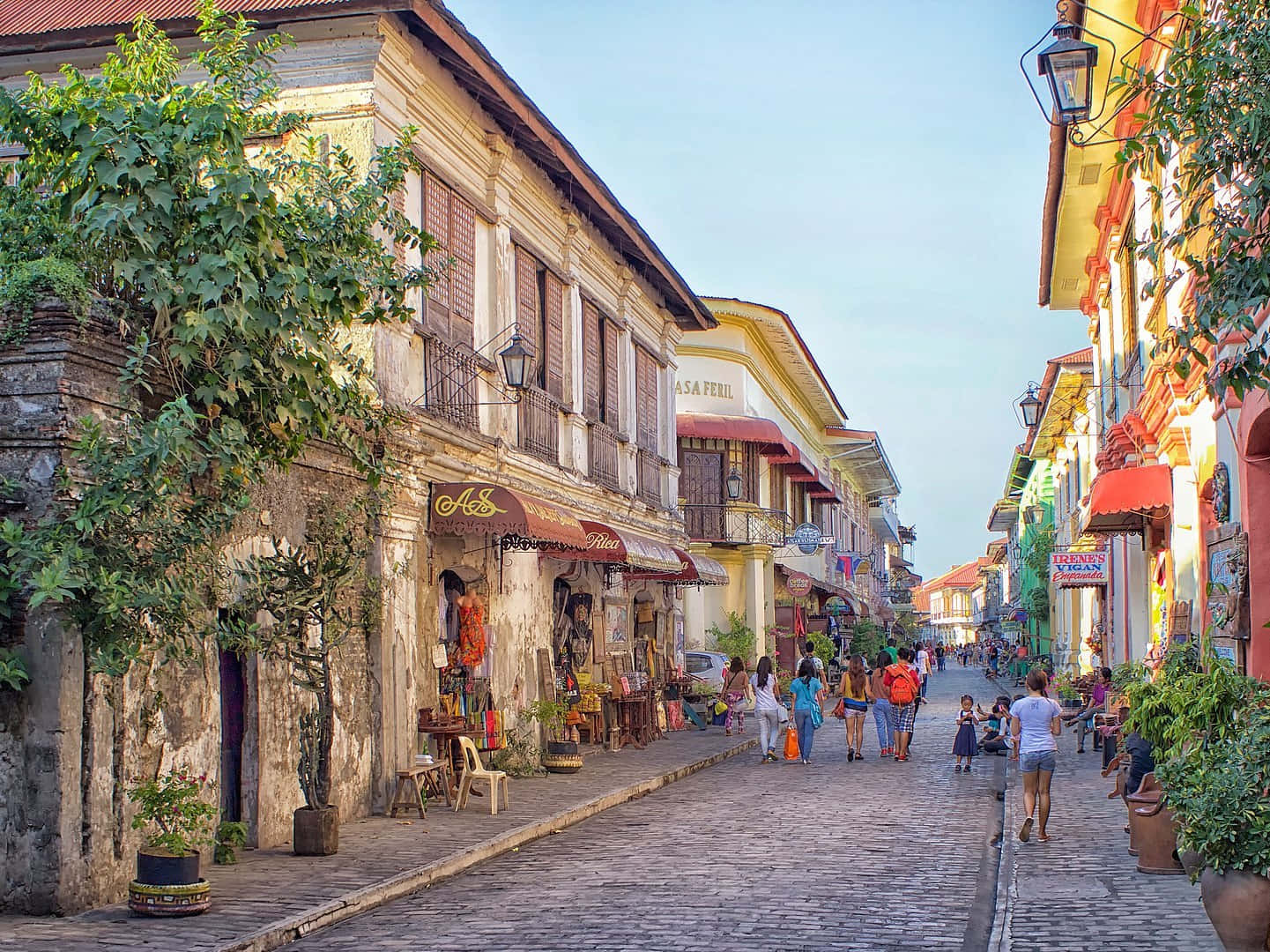 Philippines 桌布 壁紙 — 一條充滿活力的鵝卵石街道，兩旁是色彩繽紛的殖民時期建築，在晴朗的藍天下，行人熙來攘往。