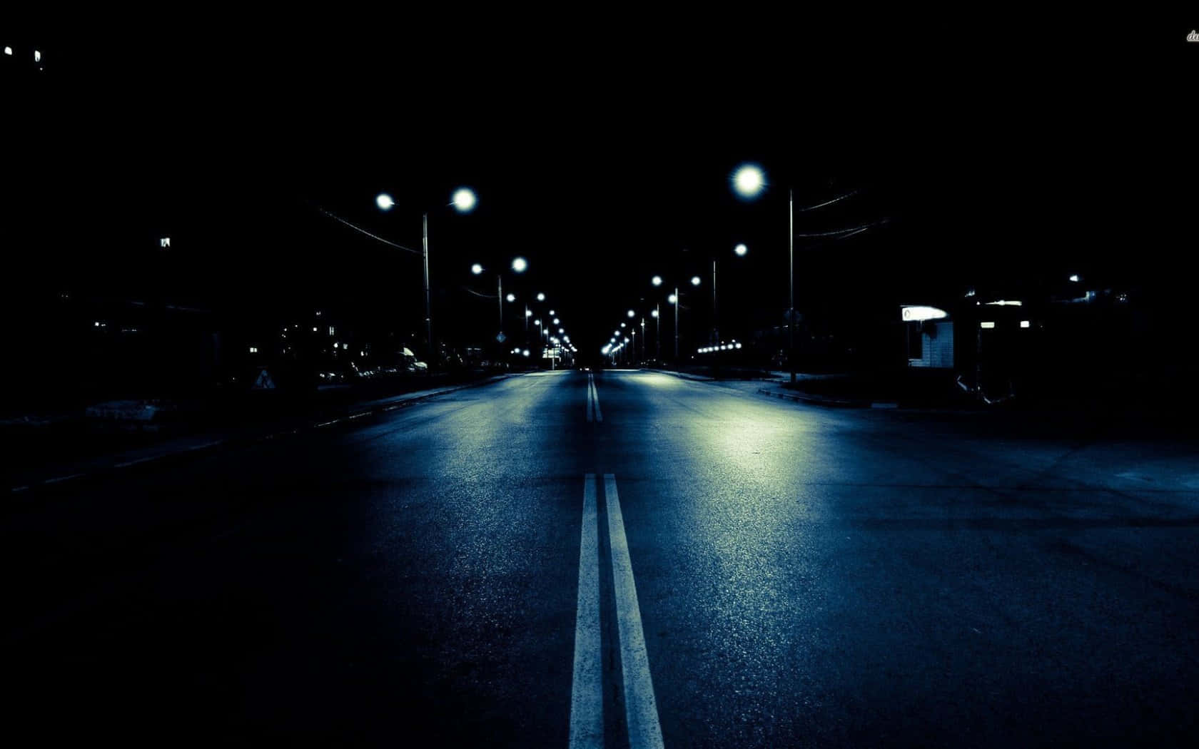 暗夜城市 桌布 壁紙 — 一條孤獨的空蕩道路在閃爍的路燈下延伸至黑暗，路燈在濕漉漉的瀝青上投射出藍色倒影。
