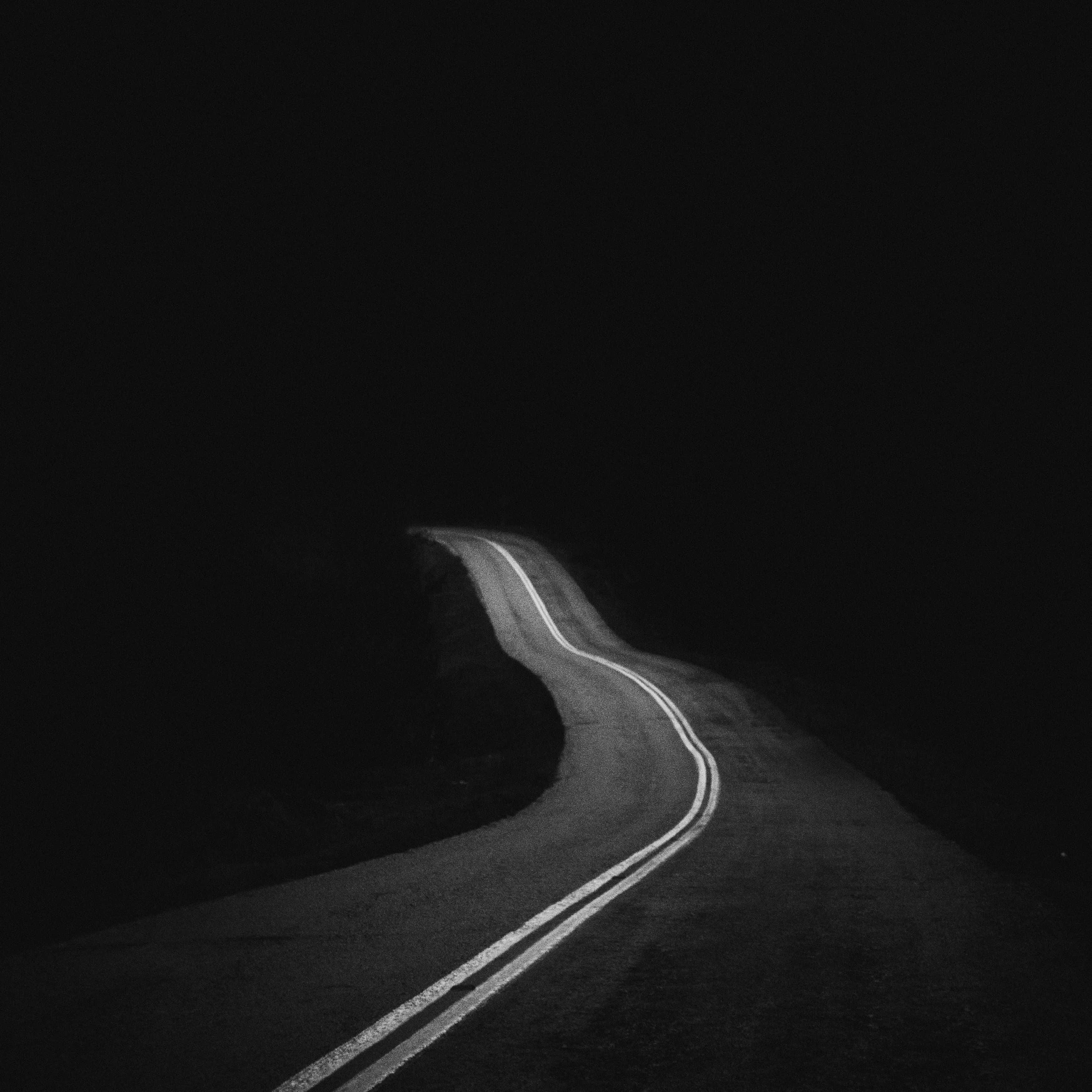 Dark Road 桌布 壁紙 — 一條孤獨蜿蜒的道路在清晰的黑白夜空下彎曲進入黑暗。