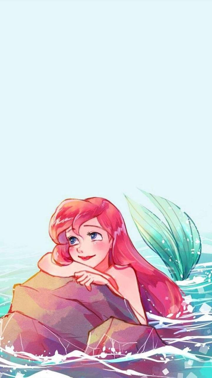 Ariel 桌布 壁紙 — 一條快樂的長紅髮綠尾美人魚在清澈的碧綠水中，在柔和的藍天下，在岩石上休息。