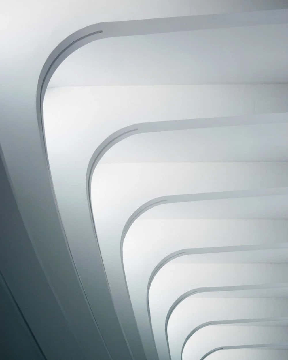 Retina Display 桌布 壁紙 — 一條極簡建築風格的樓梯，帶有光滑彎曲的階梯，向上延伸至柔和散射的光線中。