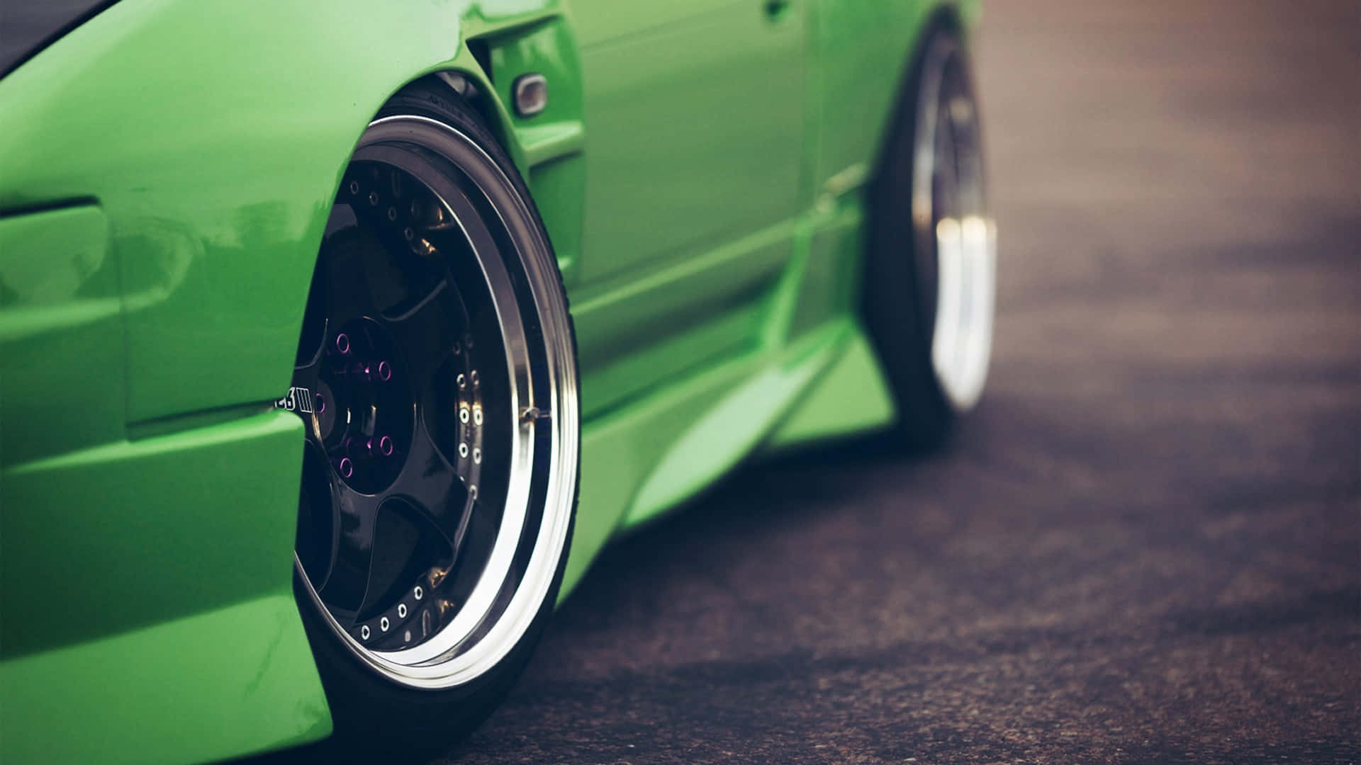 JDM 桌布 壁紙 — 一條瀝青路上鮮綠色改裝車的車輪和擋泥板特寫。