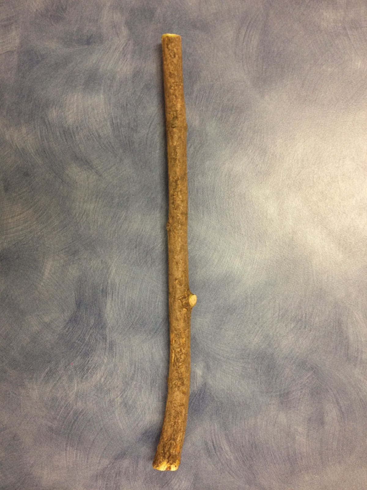 stick 桌布 壁紙 — 一條粗糙紋理的棕色小樹枝，帶有一個小節，垂直放置在斑駁的灰藍色布料背景上。