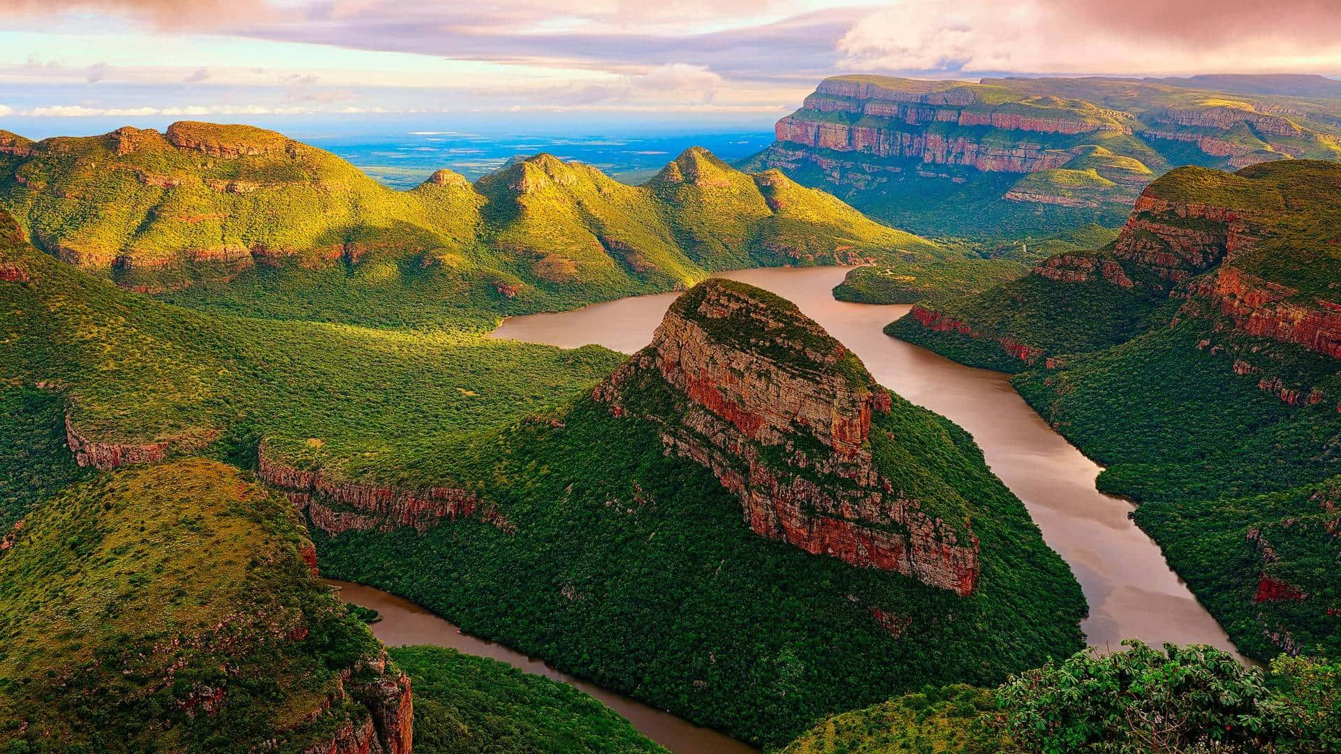 African Landscapes 桌布 壁紙 — 一條蜿蜒的河流在柔和的金色日落天空下，穿過鬱鬱蔥蔥的綠色山脈。
