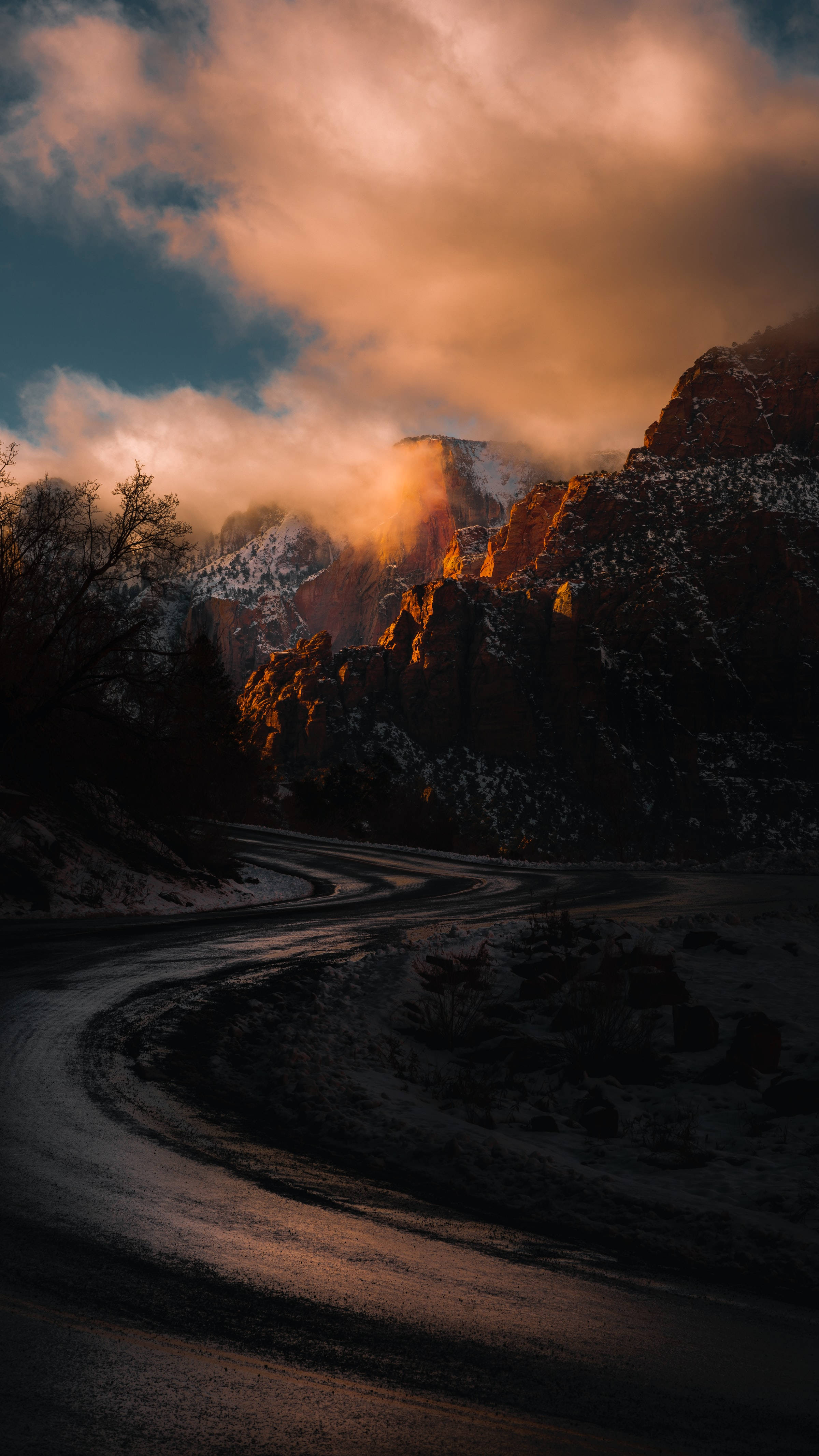 夕陽穿過雲層，照耀在積雪山脈中的蜿蜒道路上。 — 雲朵 壁紙