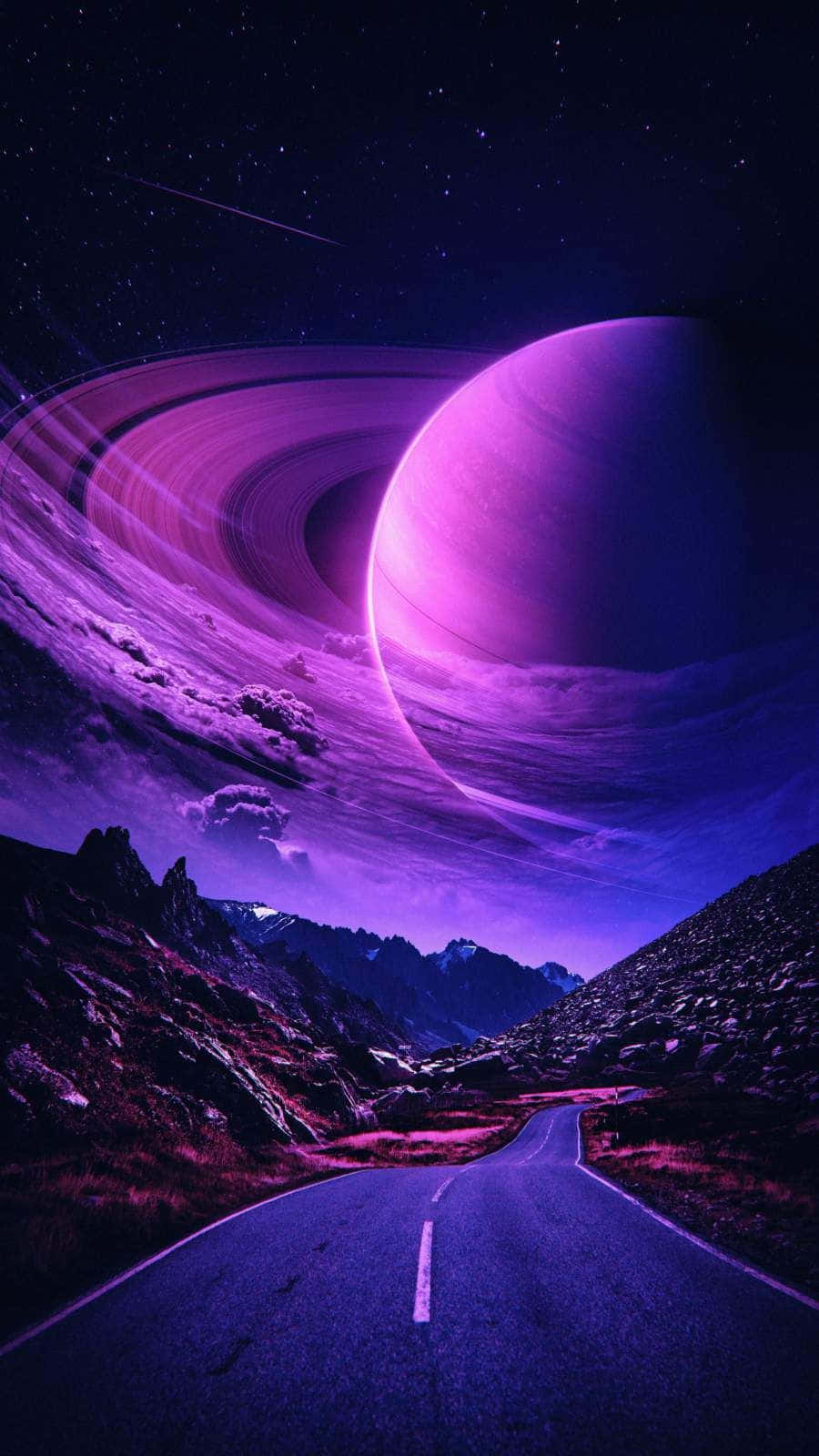 土星 桌布 壁紙 — 一條蜿蜒的道路穿過紫色的山脈，下方是一個巨大的環狀行星，在繁星點點的夜空中閃耀。