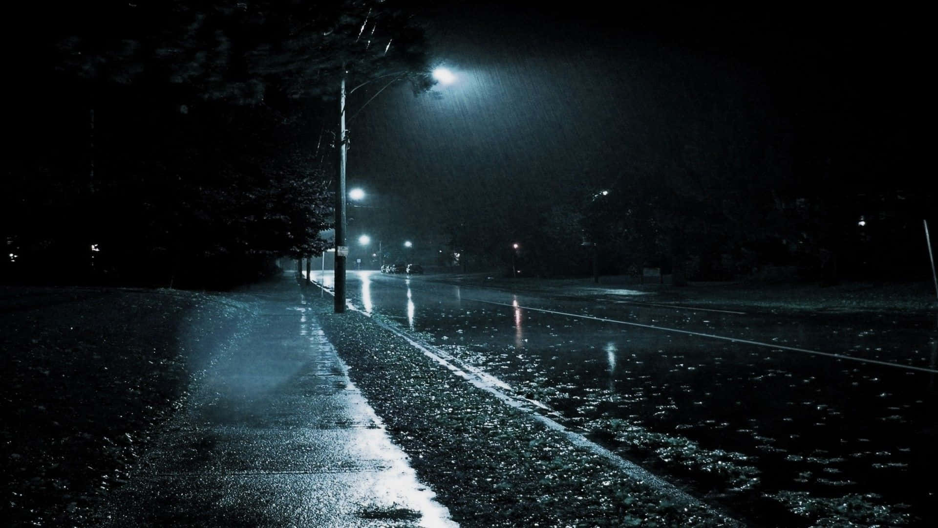 Raining 桌布 壁紙 — 一條被雨水打濕的夜間城市街道，被刺眼的路燈照亮，在落雨中投下長長的影子。