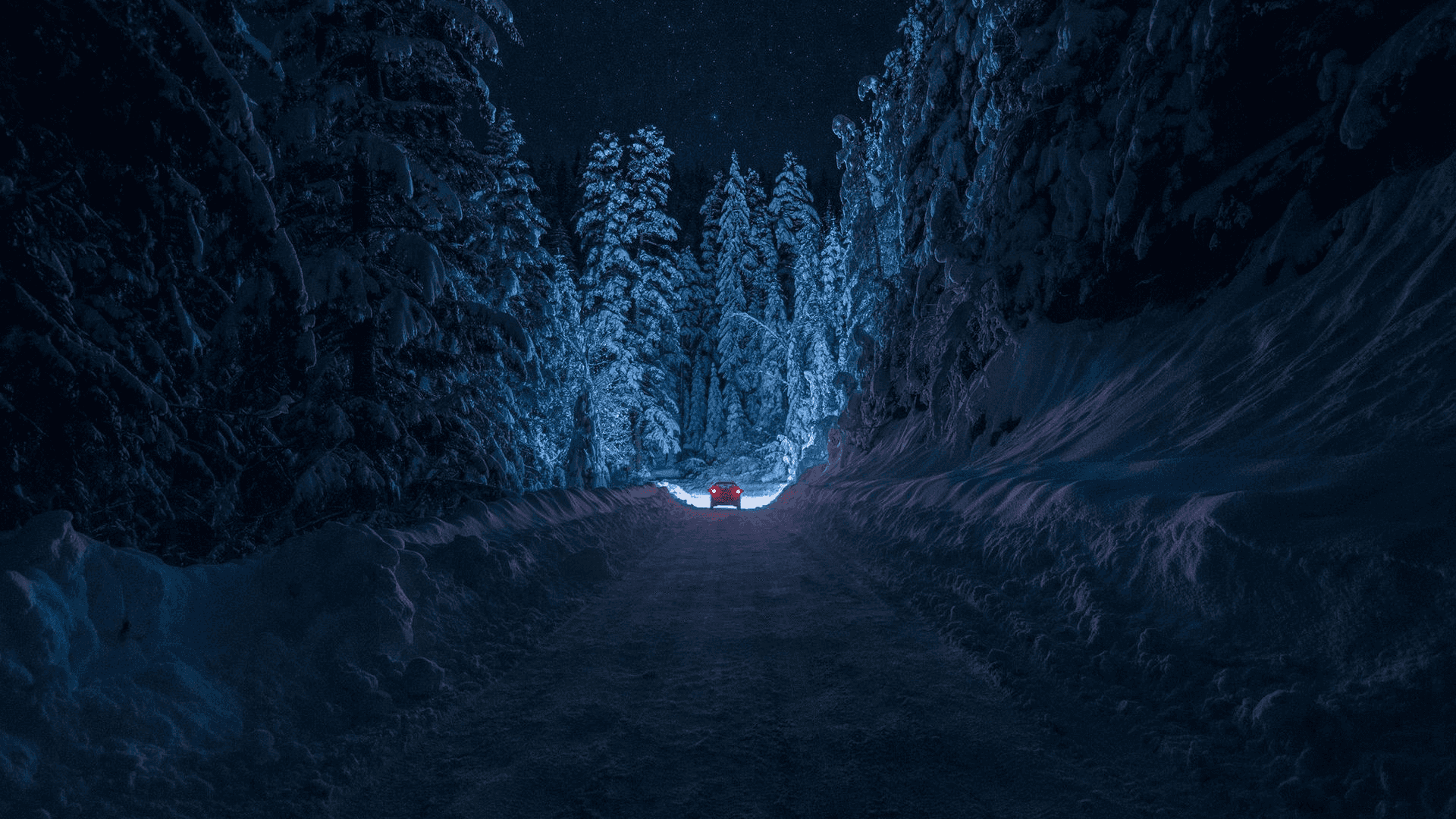 一條覆蓋雪的路，中間有一盞藍色燈光 壁紙
