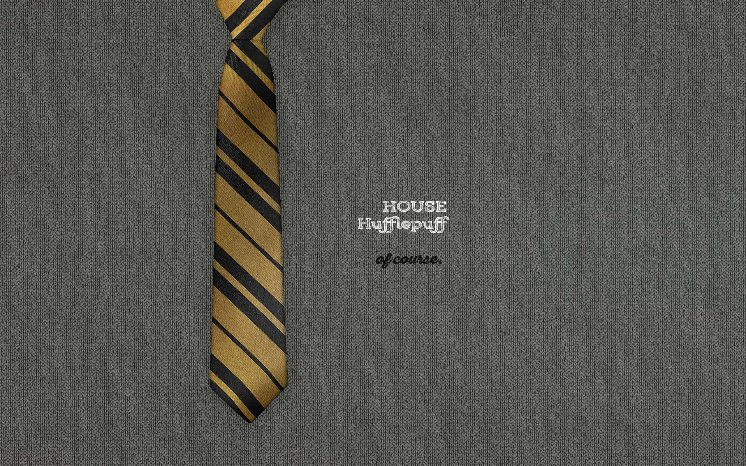 hufflepuff 桌布 壁紙 — 一條金色和黑色條紋的赫夫帕夫領帶放在一件帶有刺繡學院文字的灰色紋理毛衣上。