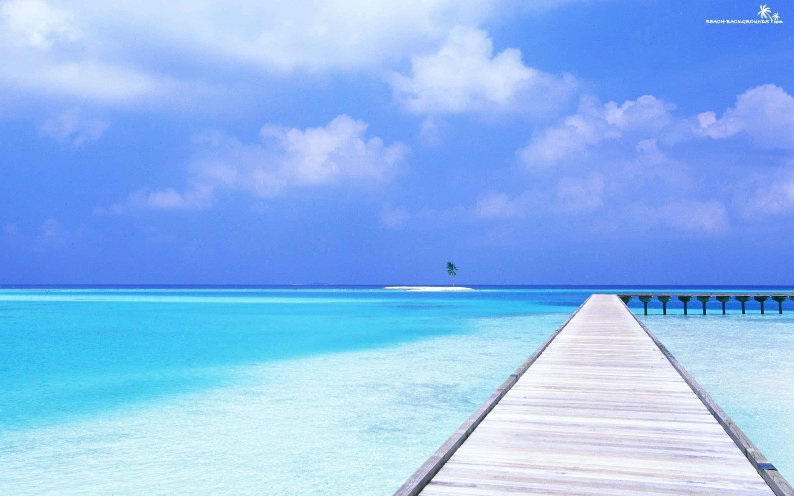 Beautiful Ocean 桌布 壁紙 — 一條長長的木碼頭延伸到清澈的碧綠海水之中，上方是明亮的藍天和蓬鬆的白雲。