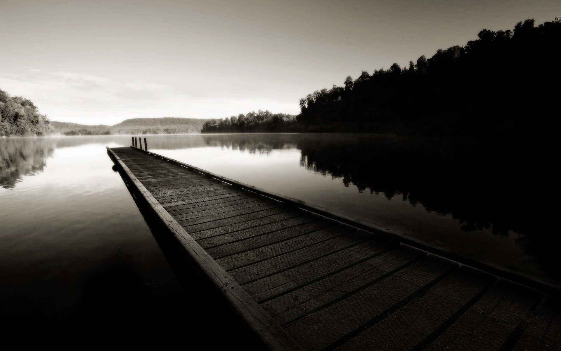 Black And White Landscape 桌布 壁紙 — 一條長長的木碼頭延伸到黎明時分霧氣瀰漫的湖中，岸邊有樹木的剪影。