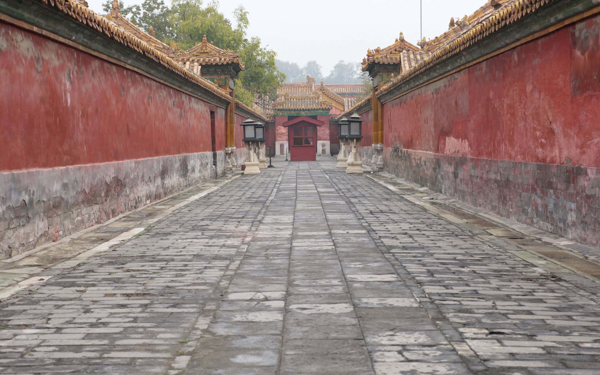 Stone Wall 桌布 壁紙 — 一條長長的石徑，兩旁是風化的紅牆，在陰天之下通往一個傳統的中國門樓。