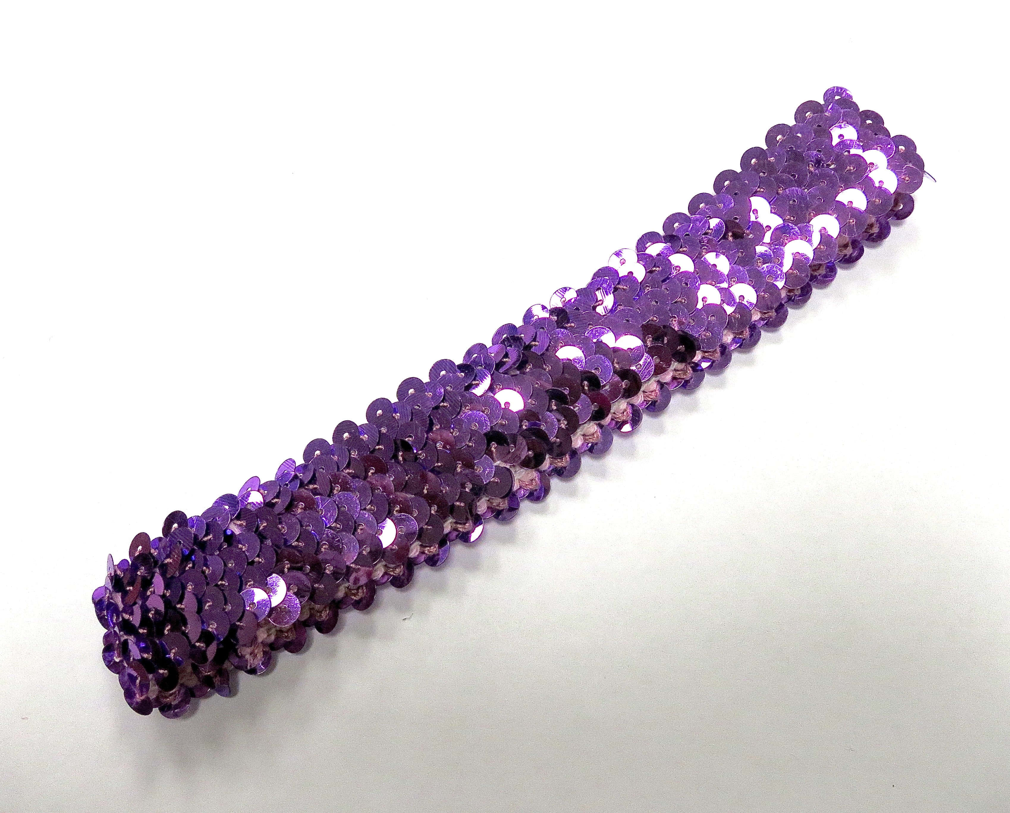 Purple Sequins 桌布 壁紙 — 一條閃爍紫色亮片的斜紋帶在純白背景上捕捉光線。