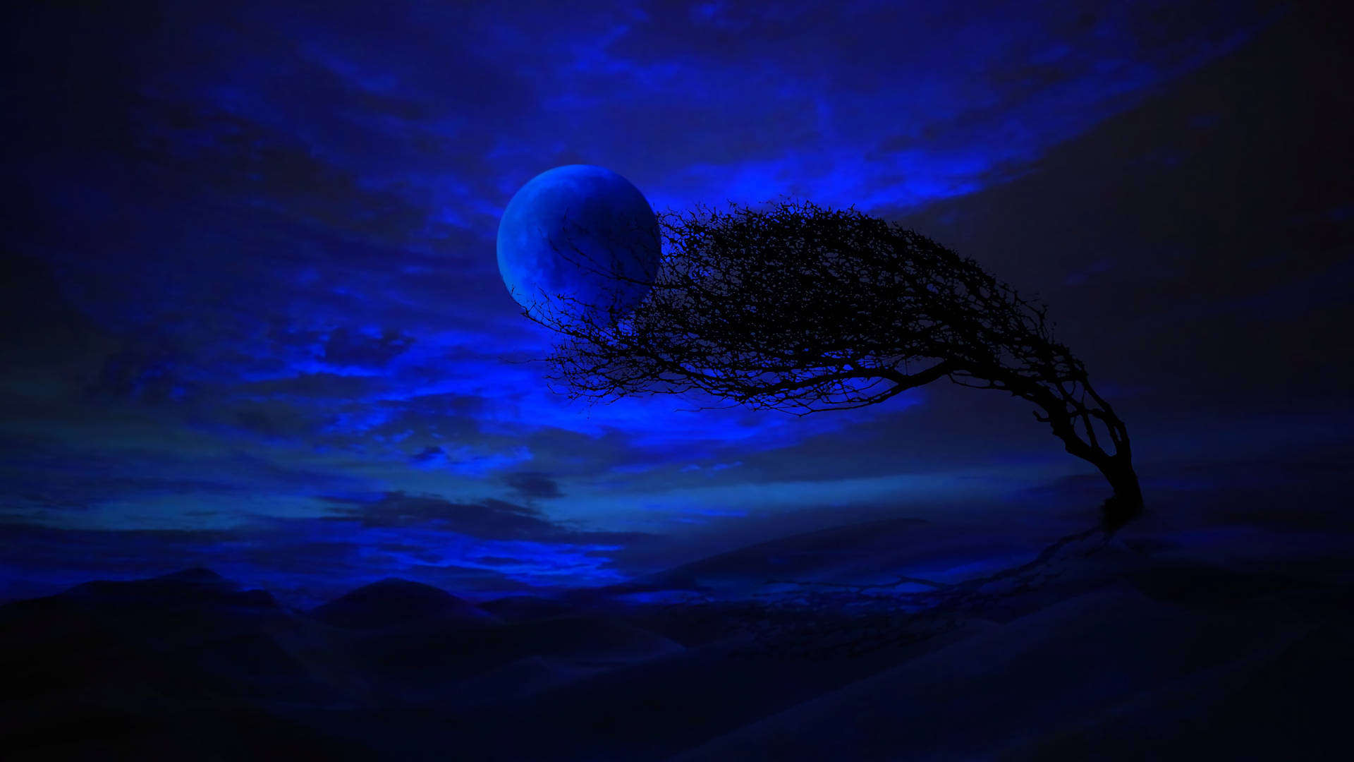 夜空 桌布 壁紙 — 一棵孤獨扭曲的樹在深藍色夜空下形成剪影，一輪發光的月亮將空靈的光芒灑在遙遠的山脈上。