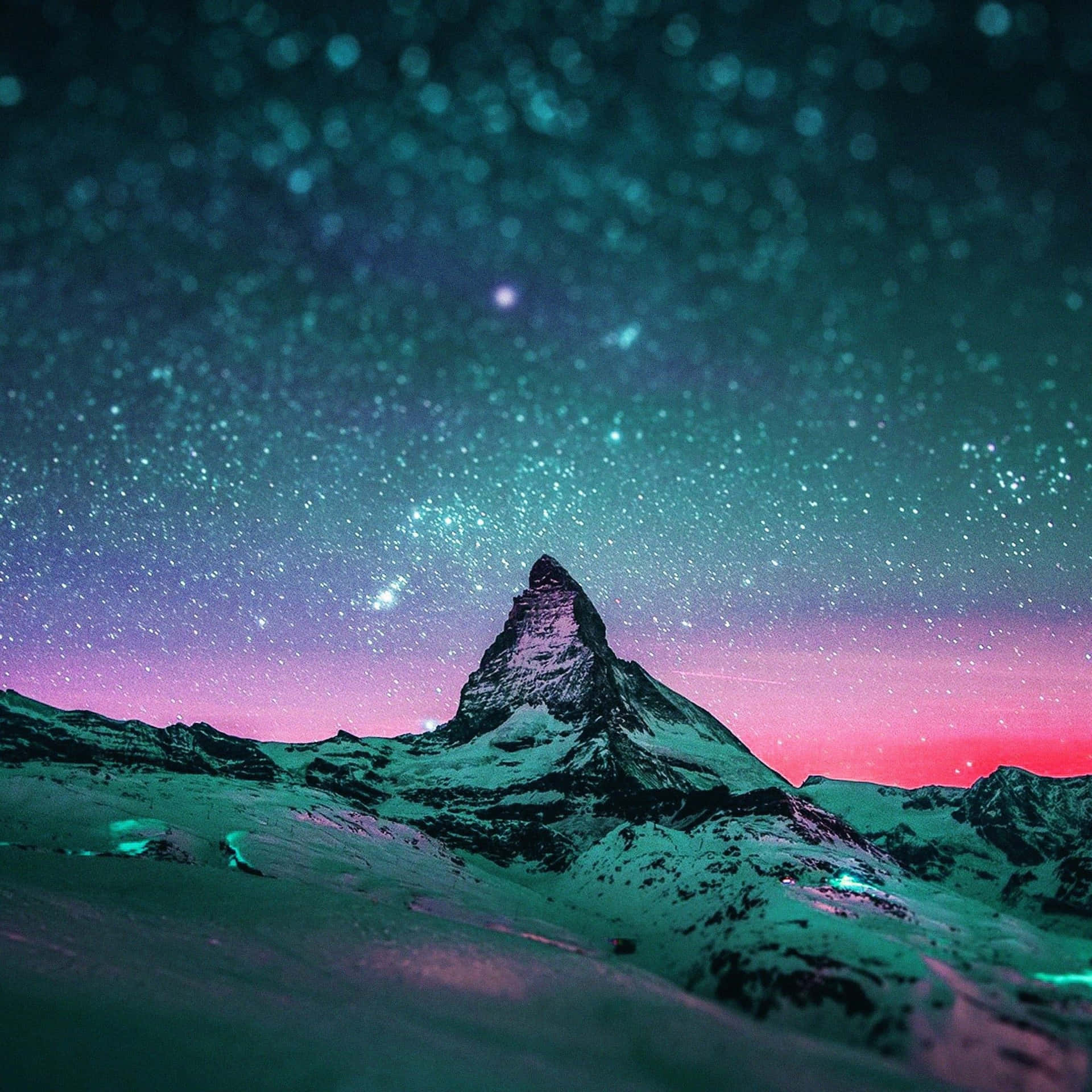 白雪覆蓋的山峰在星空下，青綠色和粉紅色的極光閃耀。