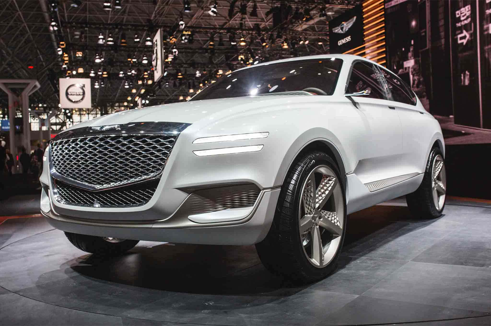 Genesis Gv80 桌布 壁紙 — 一款時尚的白色概念SUV，配有大膽的格柵和未來感車頭燈，在明亮的燈光下於汽車展覽中展示。