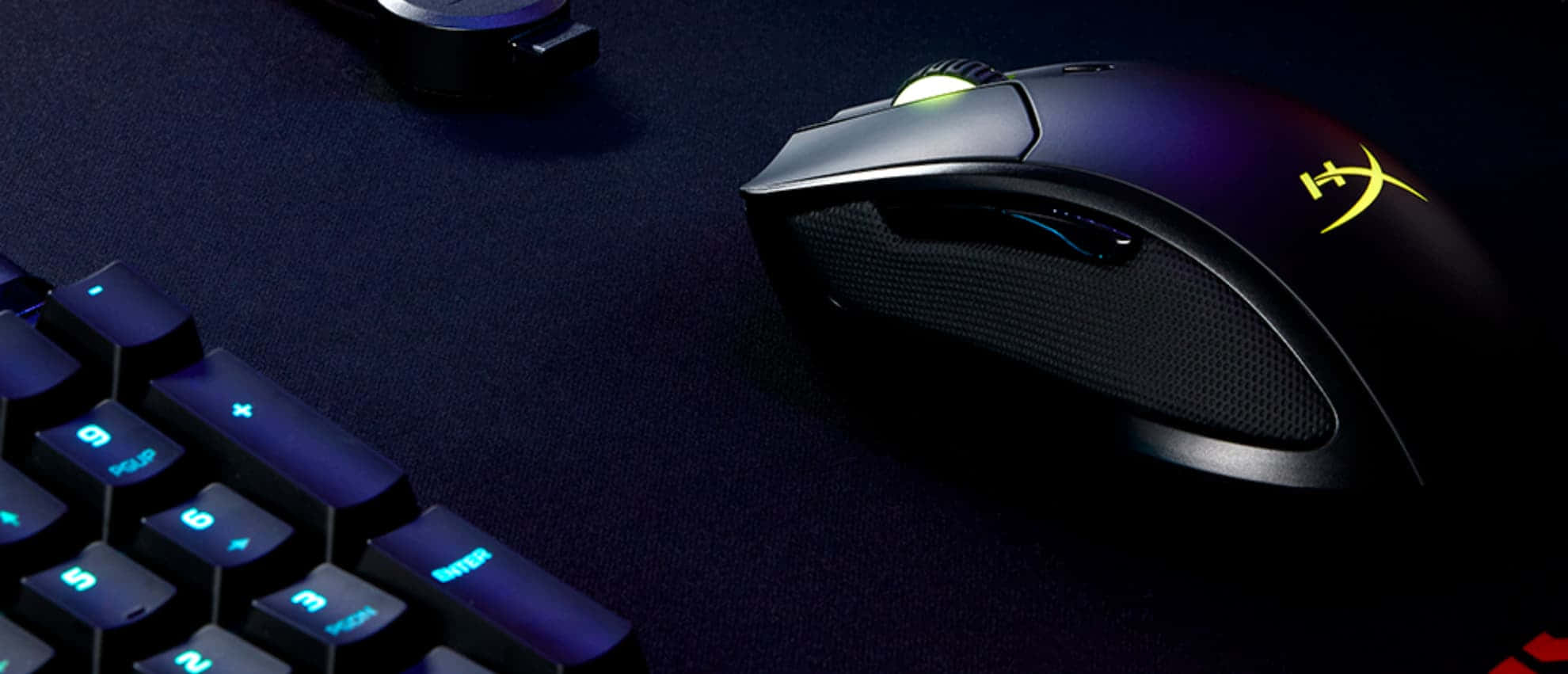 Gaming Mouse 桌布 壁紙 — 一款時尚的黑色遊戲滑鼠，帶有發光的黃色標誌，放置在一個有紋理的深色表面上，旁邊是一個帶背光的鍵盤。