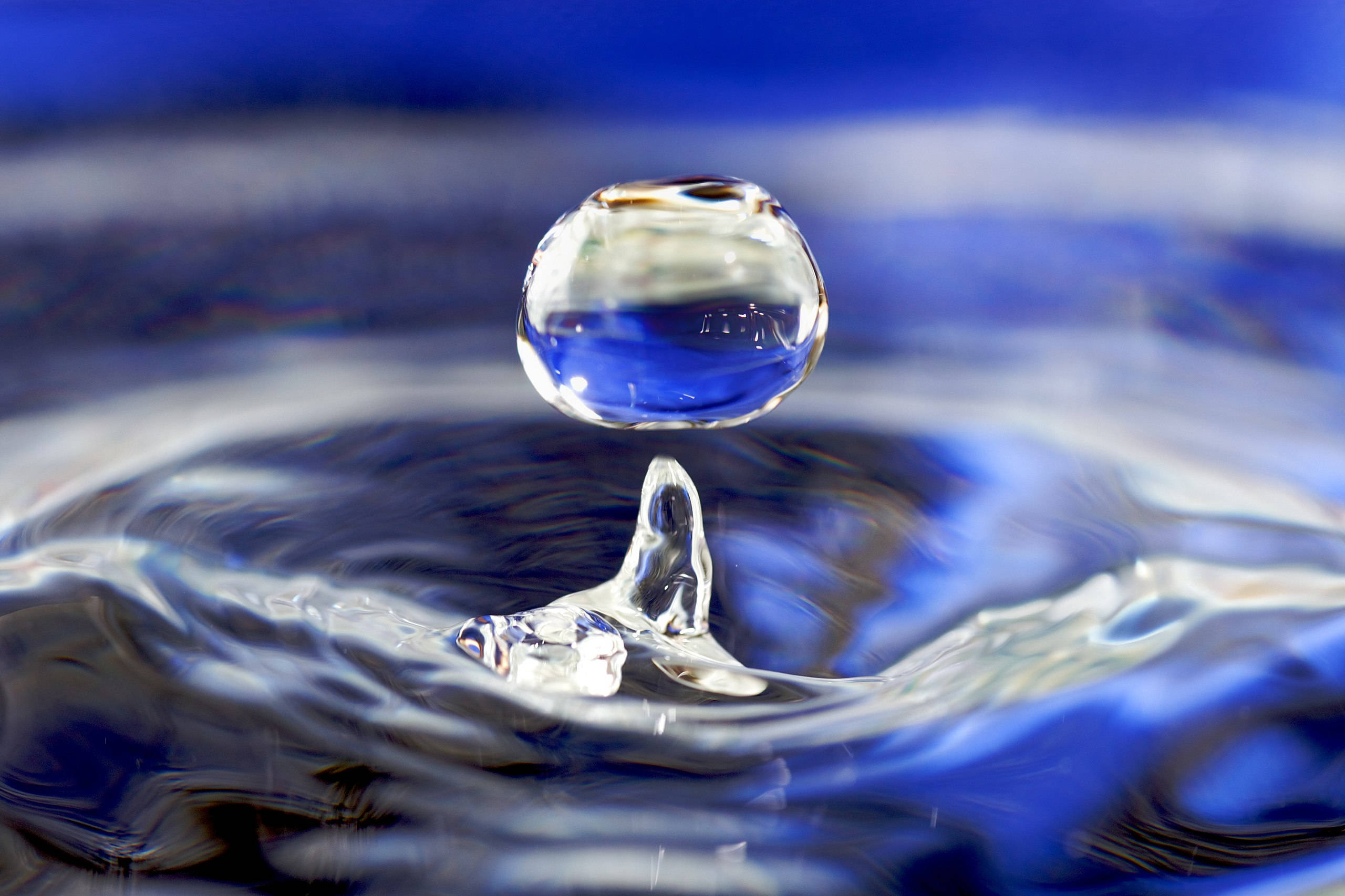Water Drop 桌布 壁紙 — 一滴完美嘅水珠懸浮喺漣漪表面之上，捕捉住深藍色嘅倒影同銳利嘅光折射。