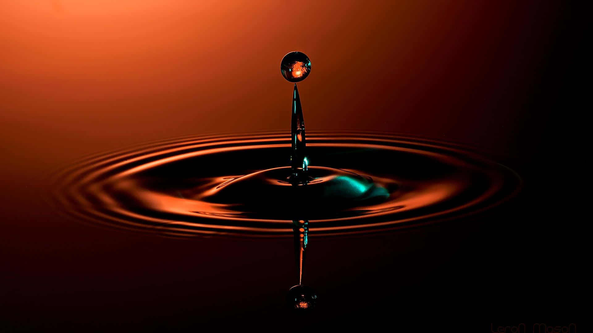 3d Water 桌布 壁紙 — 一滴完美懸浮在黑暗表面上方的水滴，在溫暖的橙色燈光下產生同心漣漪。