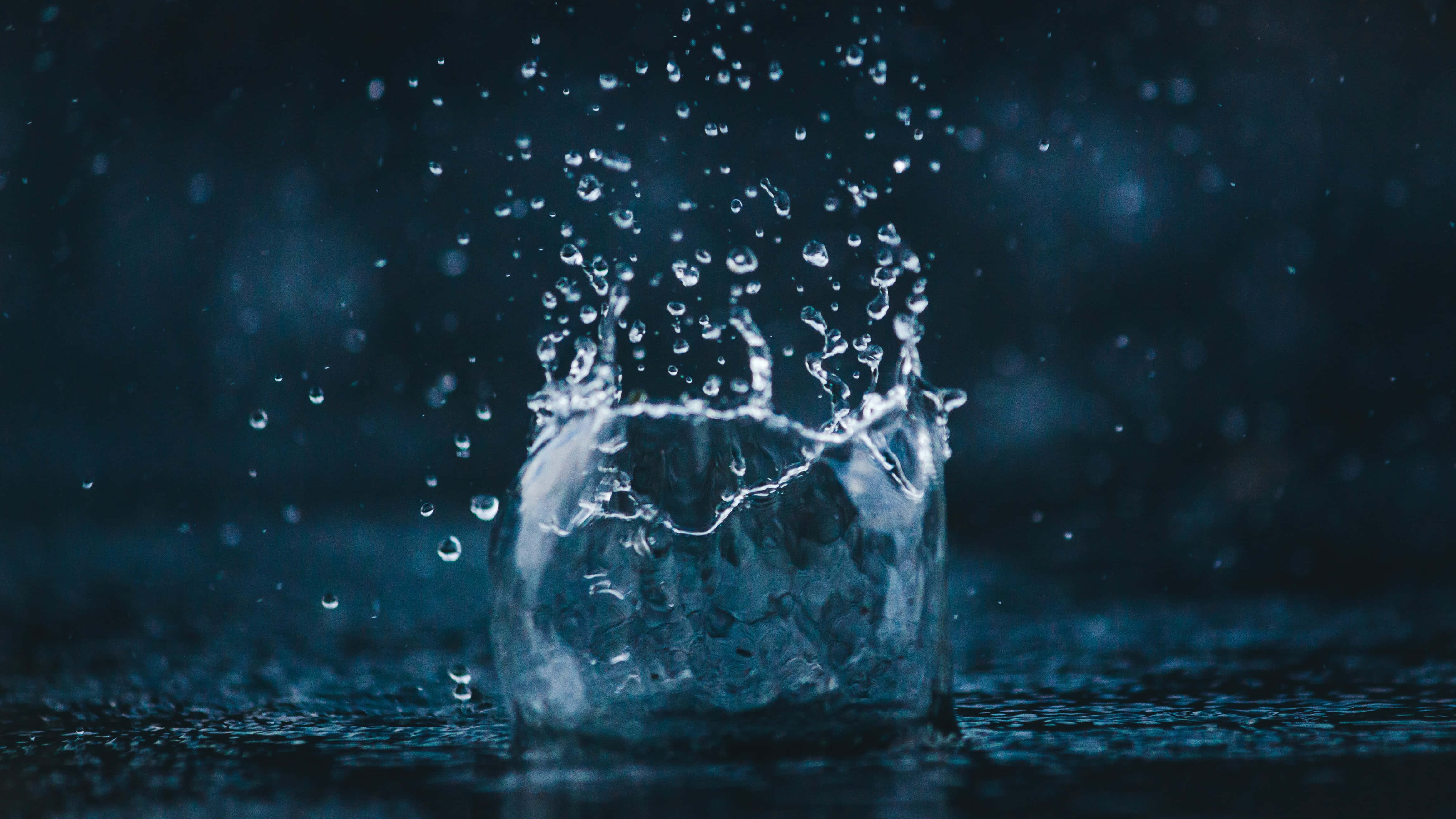 Hydration 桌布 壁紙 — 一滴水珠在水面破碎，在深藍色模糊背景上形成一頂閃爍的水珠皇冠。