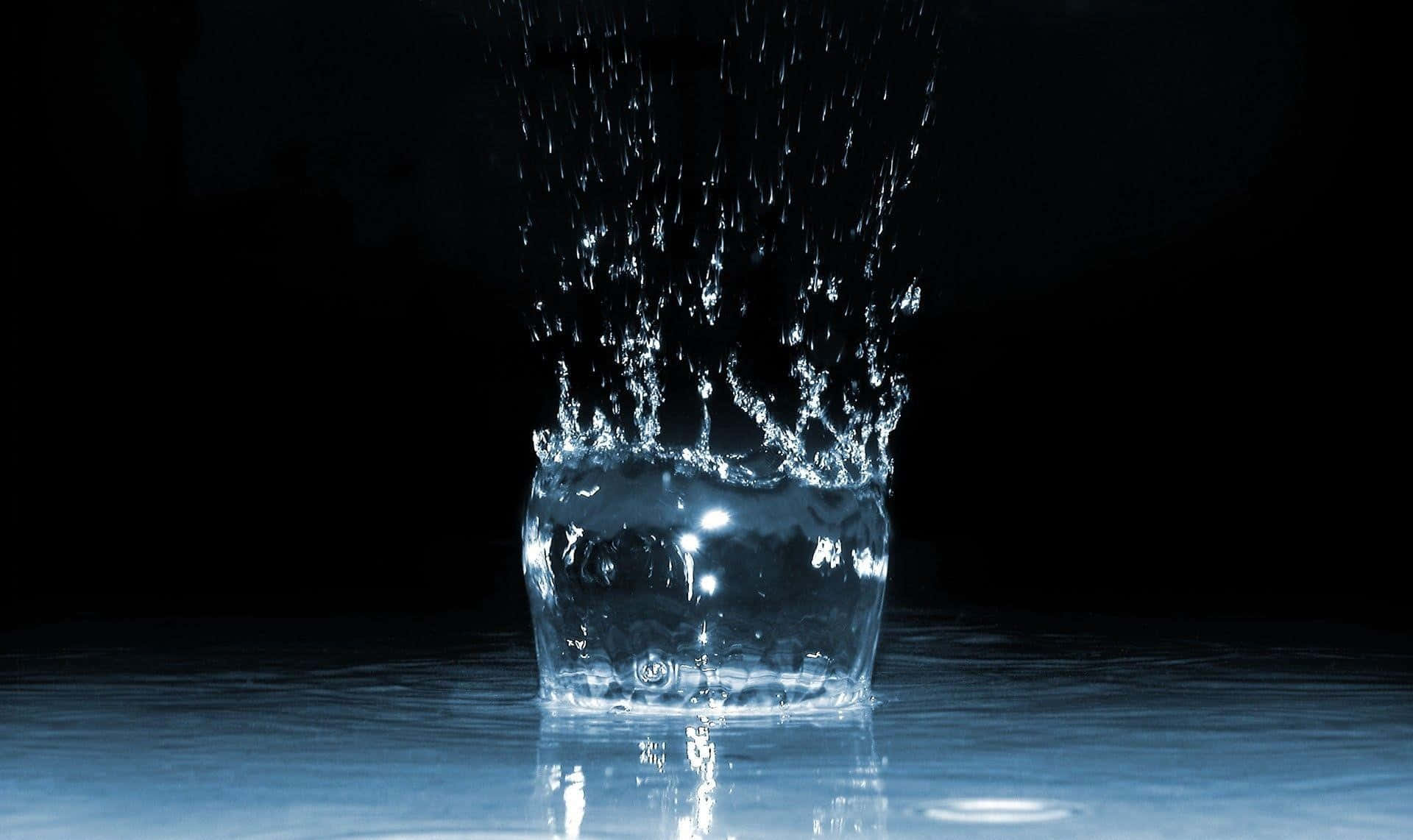一滴水的力量 壁紙 — 一滴水在黑色背景上伴隨藍色反射碎裂成閃爍的水滴。