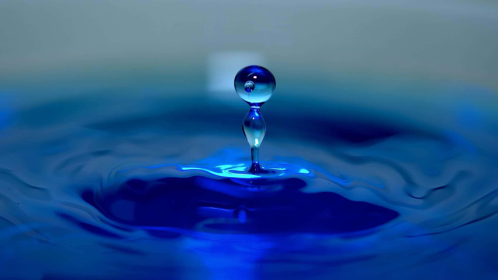 一滴藍色水滴漂浮在一碗水中 壁紙