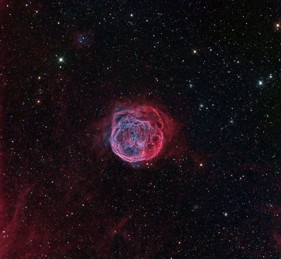 Interstellar Cloud 桌布 壁紙 — 一片充滿活力的紅色和藍色宇宙星雲在深空星場中閃耀。