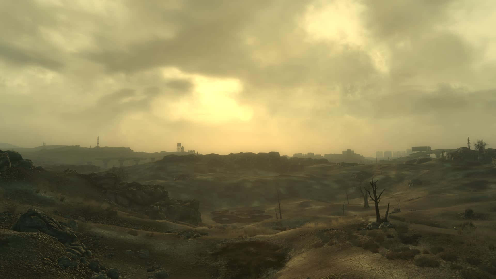 Fallout 4 The Capital Wasteland 桌布 壁紙 — 一片荒蕪之地，籠罩在朦朧的金色天空下，遠處有廢墟和枯樹。