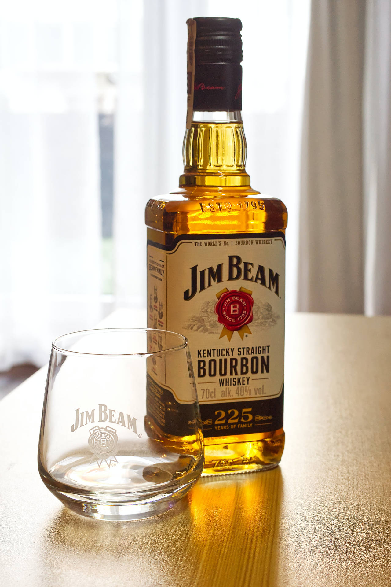 窗邊木桌上的Jim Beam波本酒瓶和酒杯。
