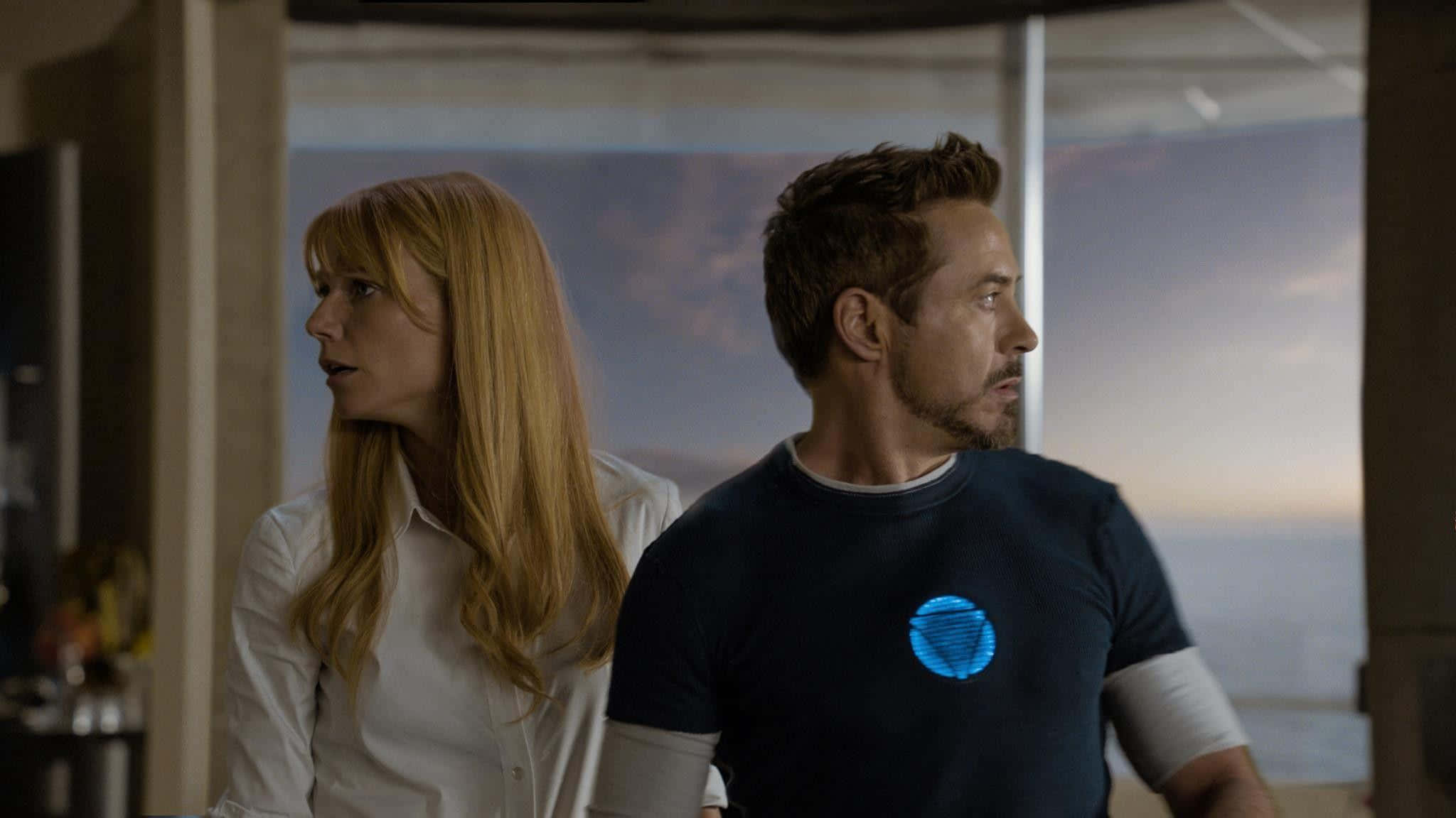 Pepper Potts 桌布 壁紙 — 一男一女並肩站在現代風格的房間裡，望向窗外暮色天空。