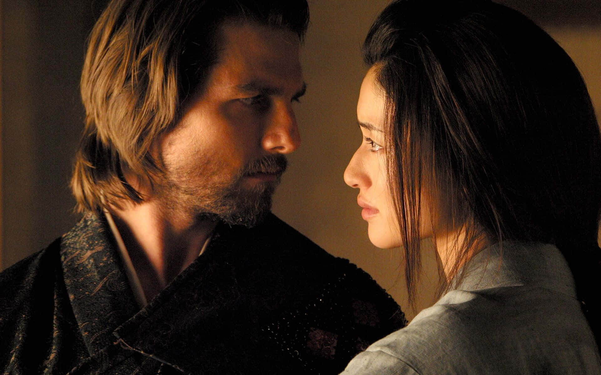Samurai Movies 桌布 壁紙 — 一男一女在溫暖的金色燈光下相對而立，在昏暗的房間中，他們的表情強烈而親密。