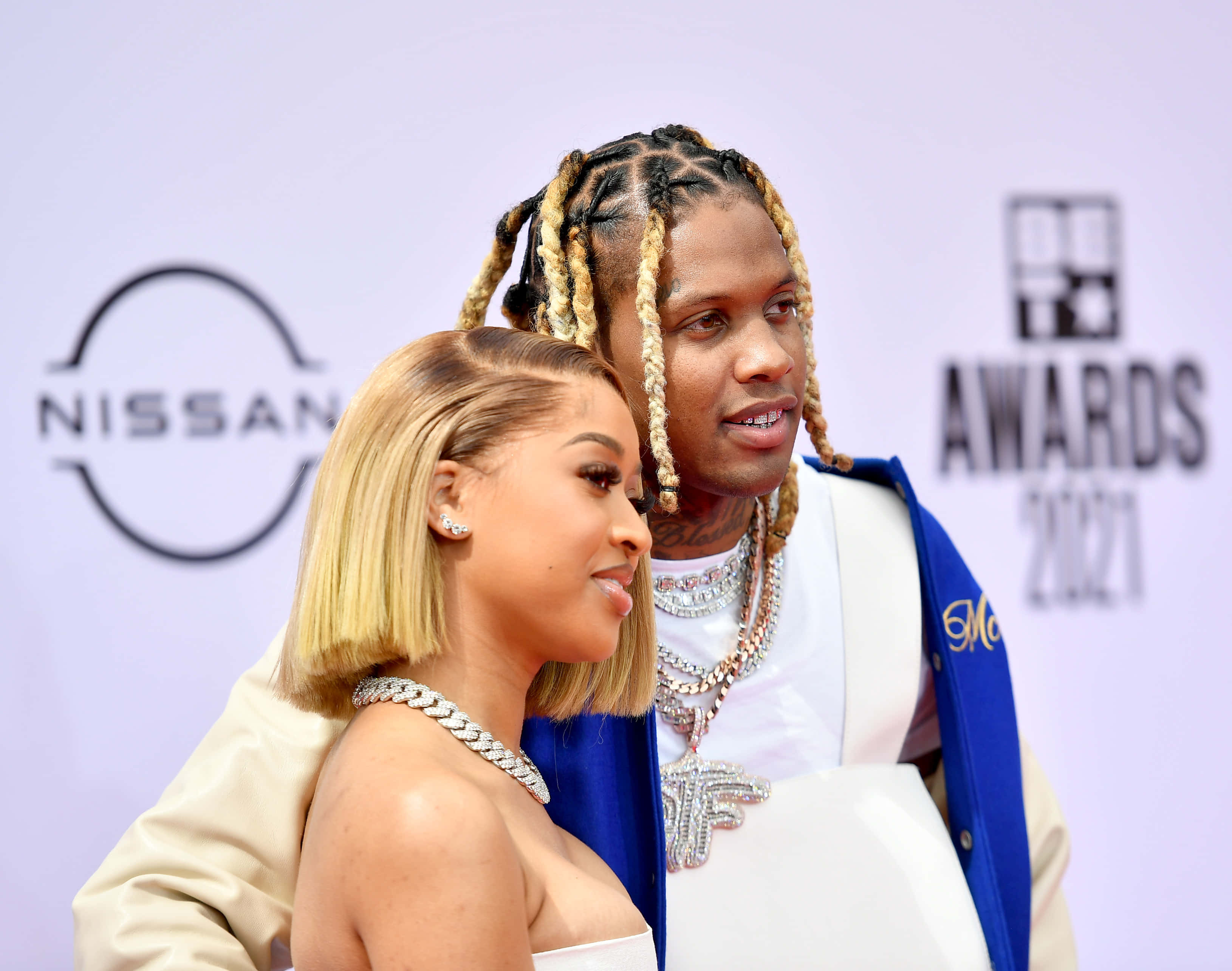 lil durk 桌布 壁紙 — 一男一女穿著華麗服裝在2021年BET頒獎典禮的紅地毯上合影，背景有日產品牌標誌。
