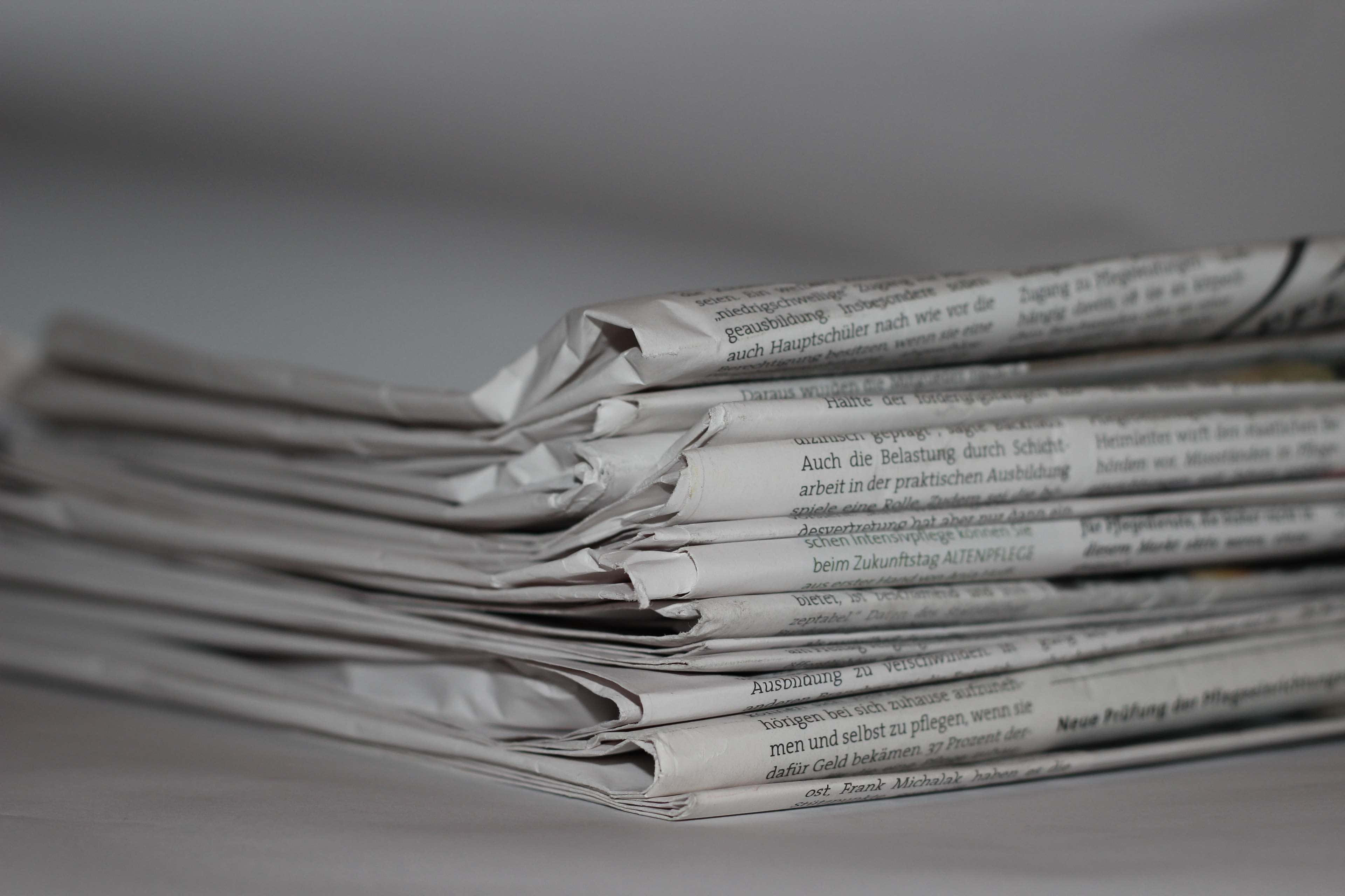 Journalism 桌布 壁紙 — 一疊折疊報紙的特寫，帶有模糊文字和柔和灰色調。