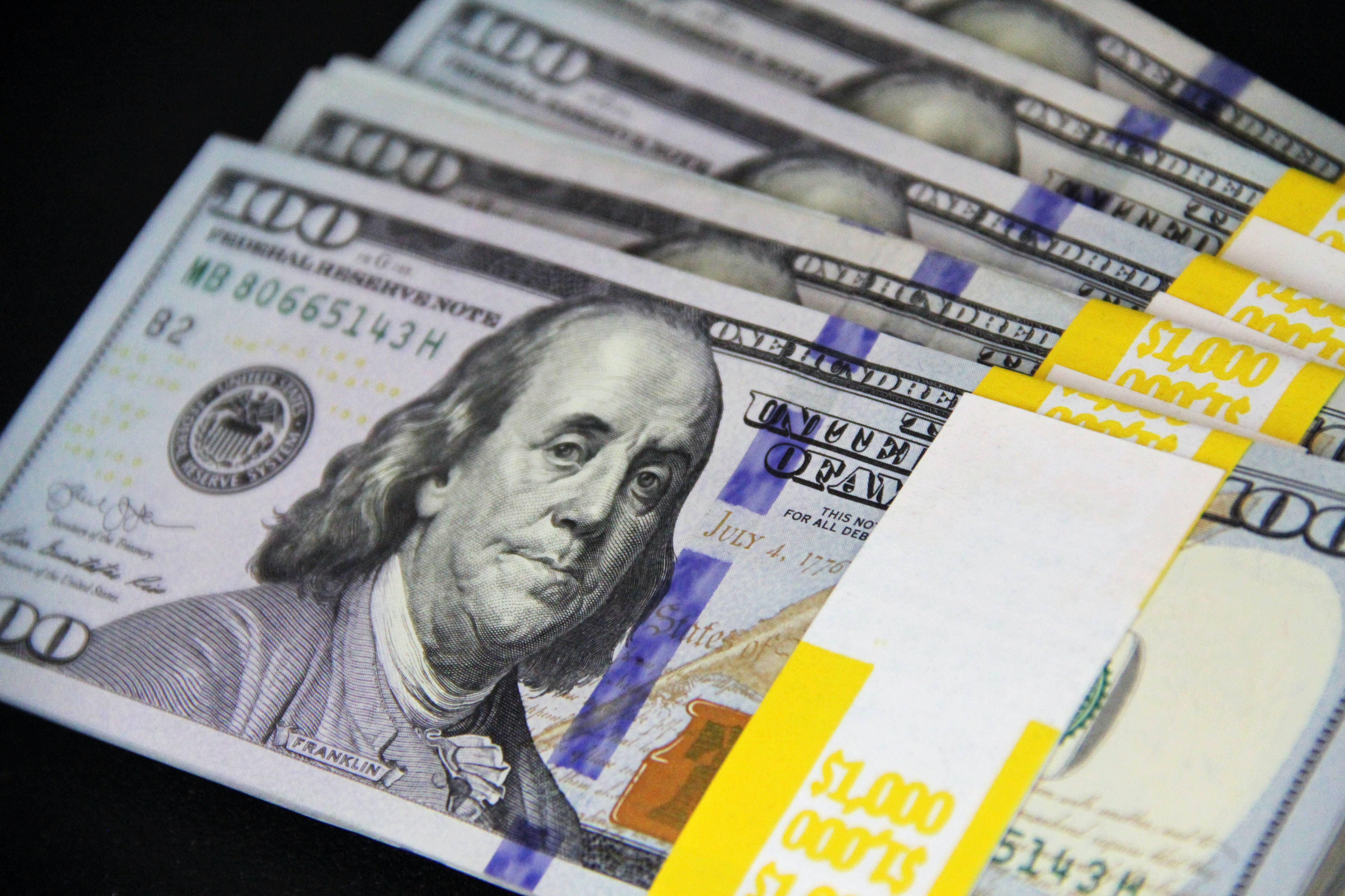 Money 桌布 壁紙 — 一疊疊用黃色帶捆紮的美國一百美元鈔票，背景深色。