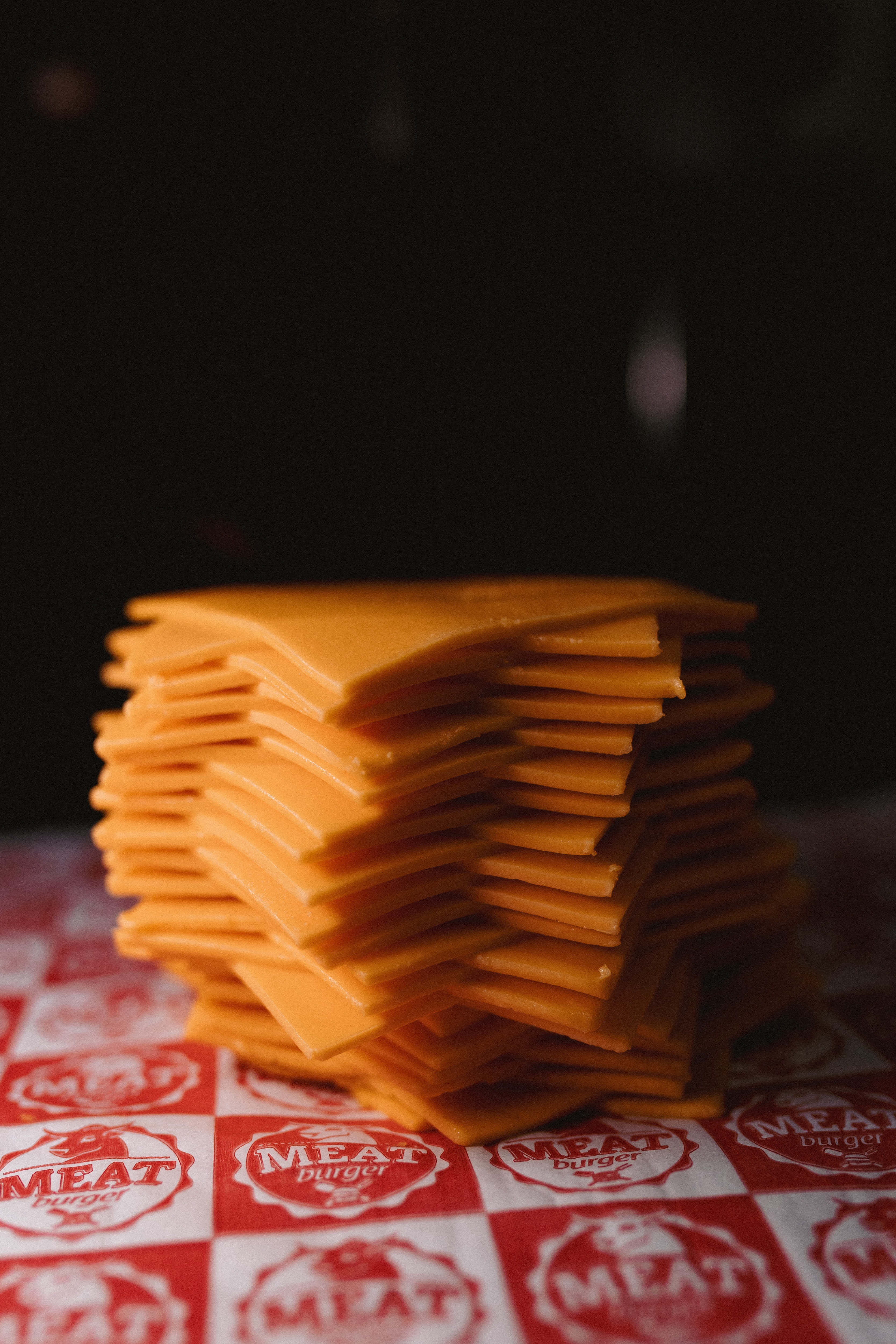 Cheese 桌布 壁紙 — 一疊高高的橙色芝士片放在紅白格仔 'MEAT burger' 紙上。