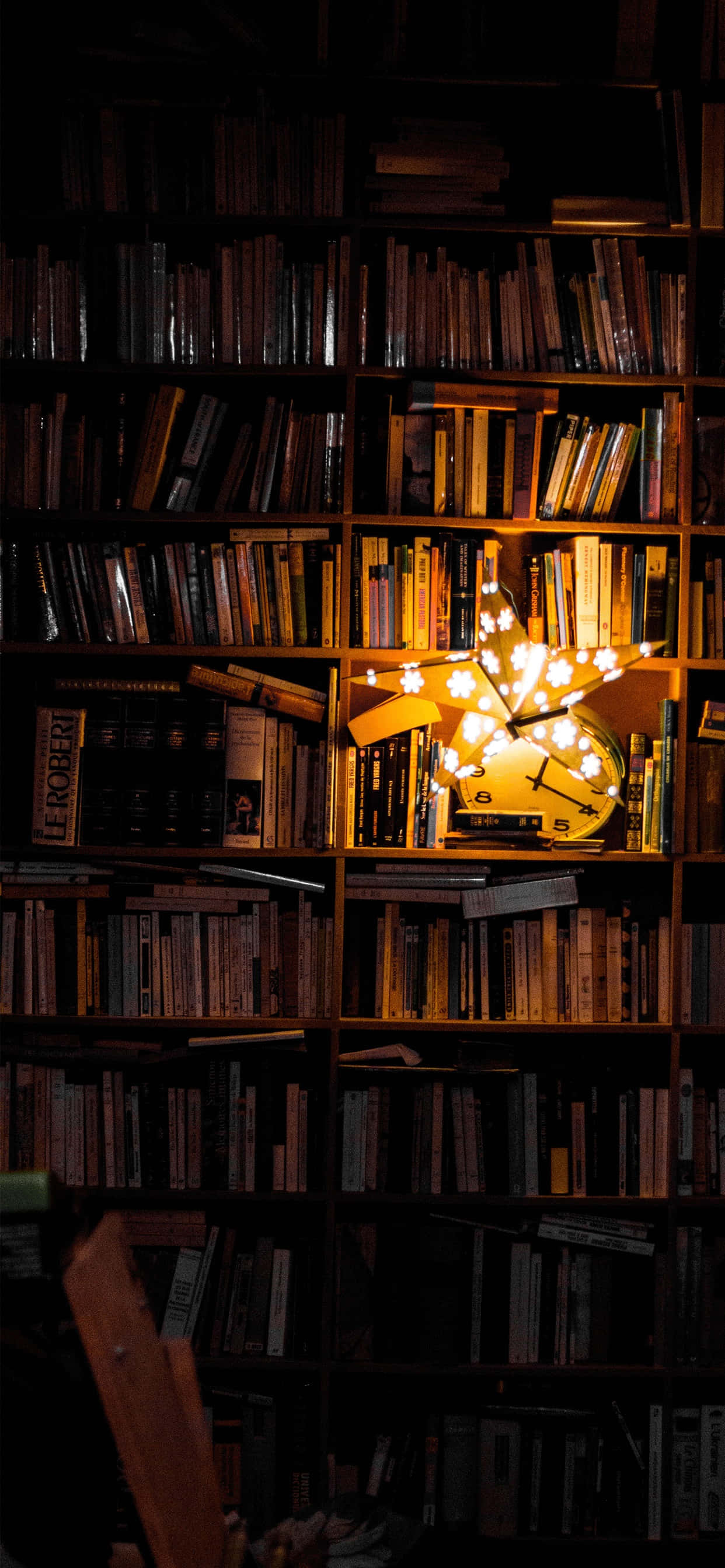 books 桌布 壁紙 — 一盞溫暖照明的星形燈在光線昏暗的圖書館中，在高聳的書架間閃耀。