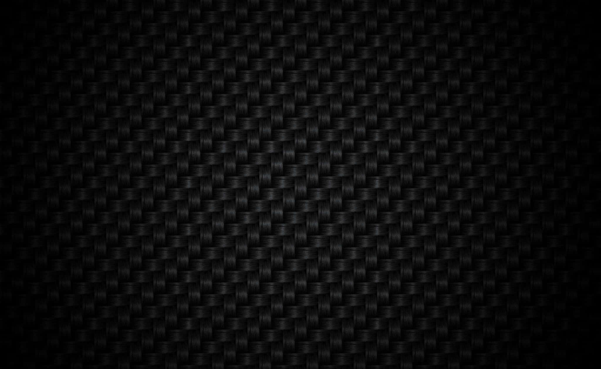一瞥經典碳纖維背景 壁紙 — 黑色碳纖維質感的特寫，帶有細微編織圖案和漸變燈光。