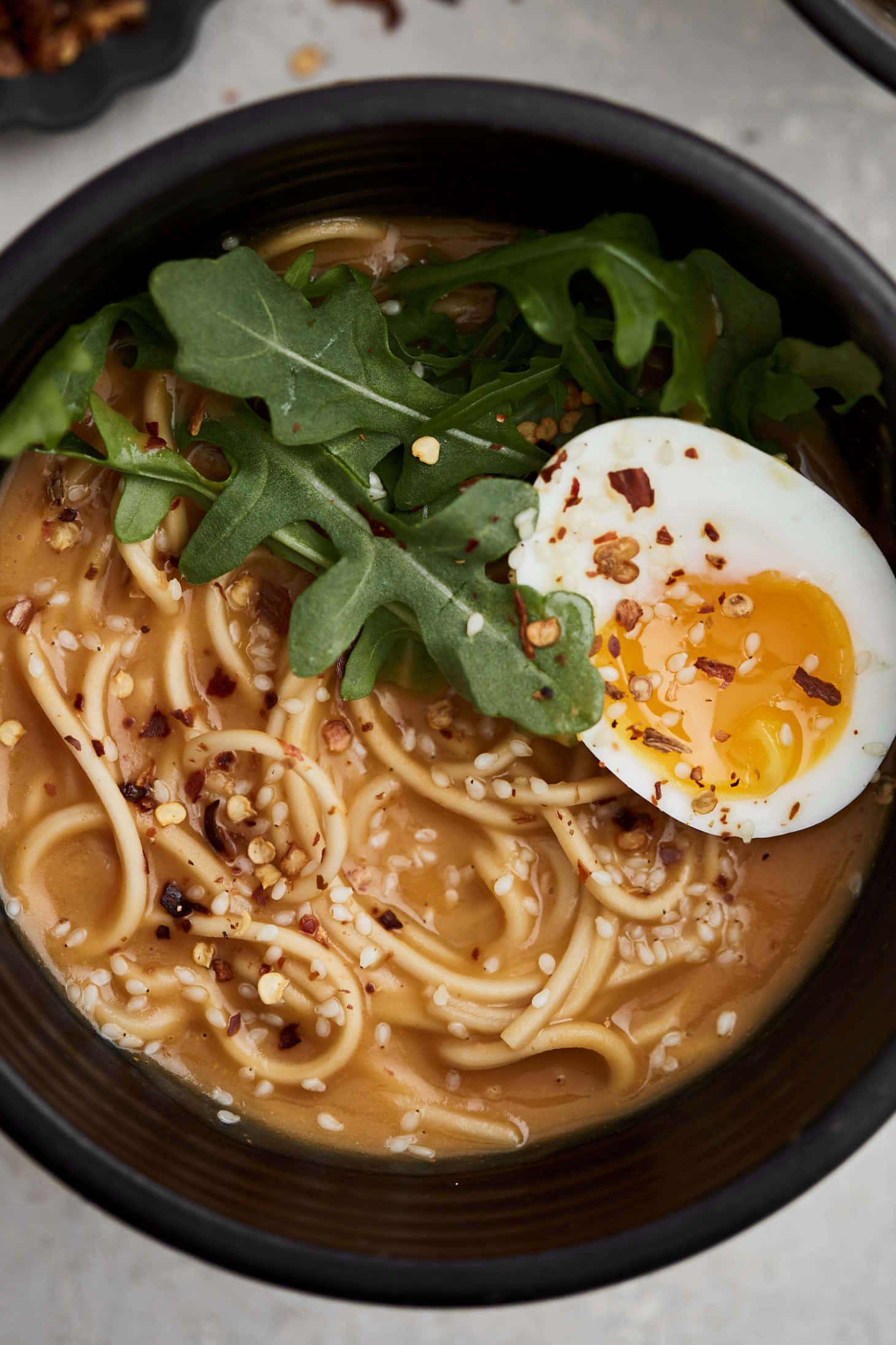 Noodles 桌布 壁紙 — 一碗熱騰騰拉麵的特寫，上面鋪上新鮮芝麻菜、芝麻和半熟蛋。