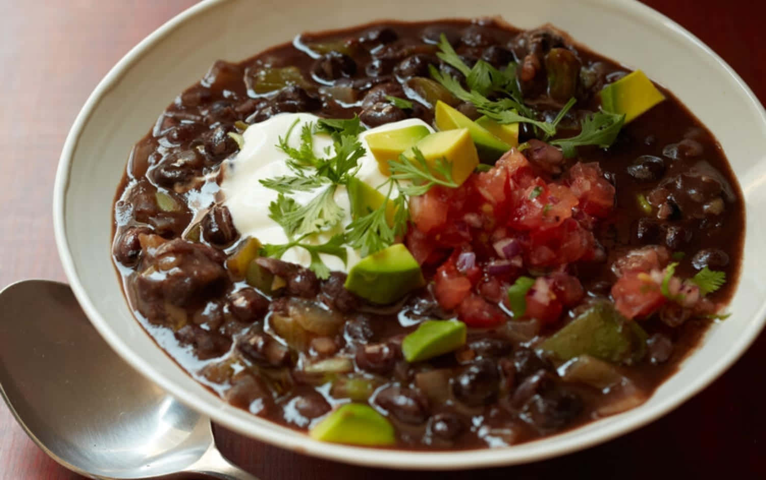 Black Bean Soup 桌布 壁紙 — 一碗熱騰騰的濃郁黑豆辣椒，上面放有酸奶油、牛油果和新鮮莎莎醬。