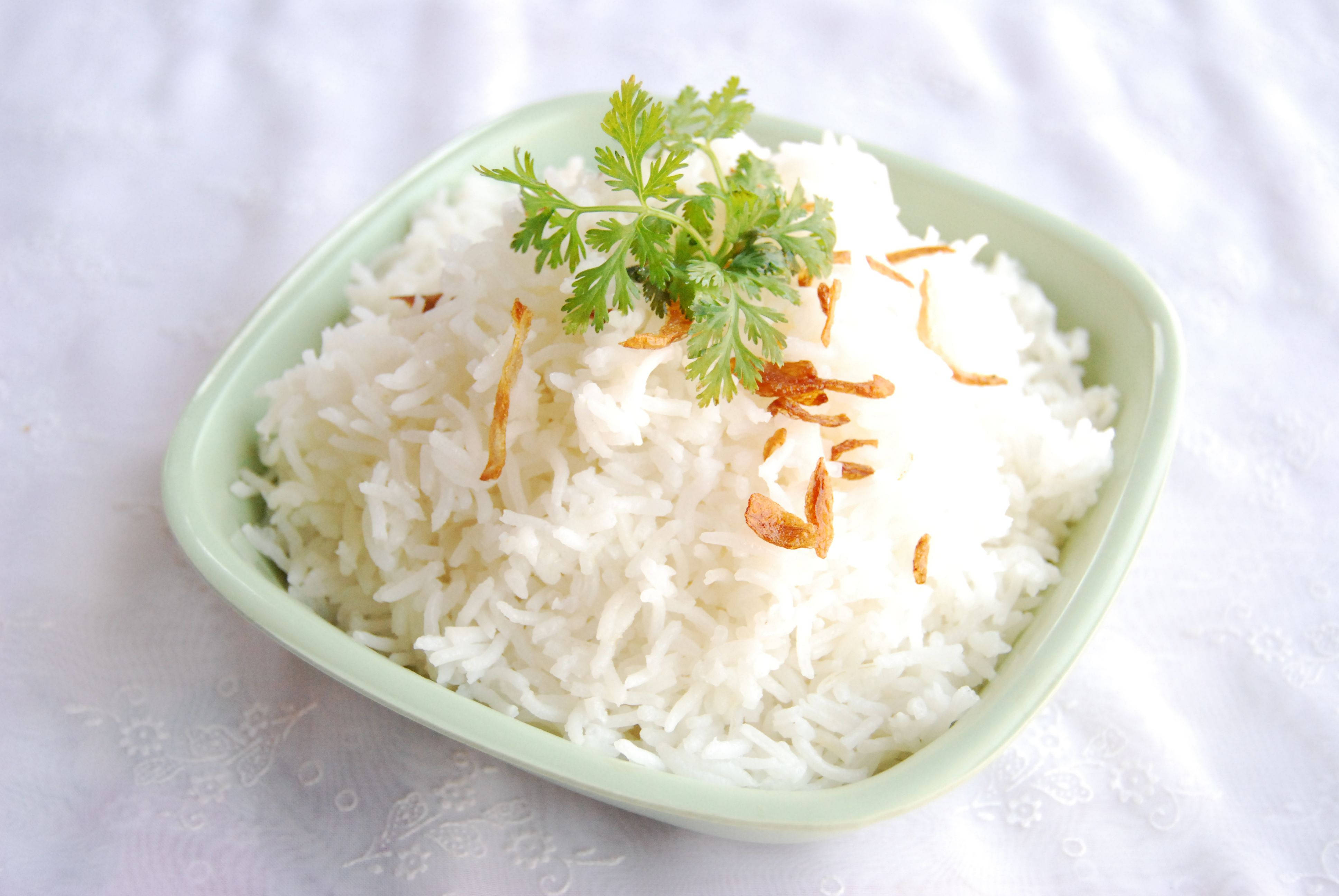 一碗白飯 壁紙 — 一個淺綠色碗盛載著鬆軟的白飯，上面放上新鮮芫荽和香脆炸乾蔥，放在有紋理的白色布上。