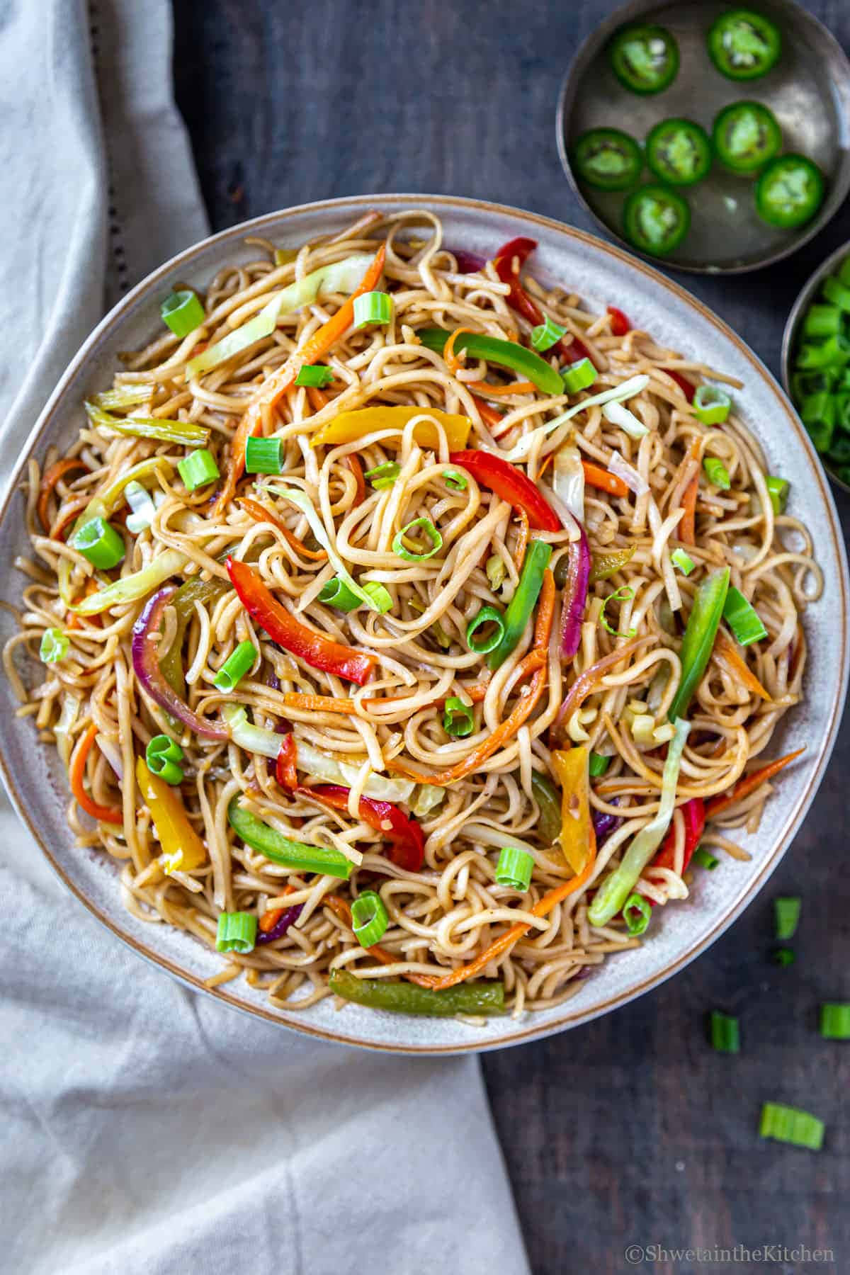 Noodles 桌布 壁紙 — 一碗色彩繽紛的炒麵，上面鋪滿了彩色甜椒和青蔥，放在質樸的木桌上。