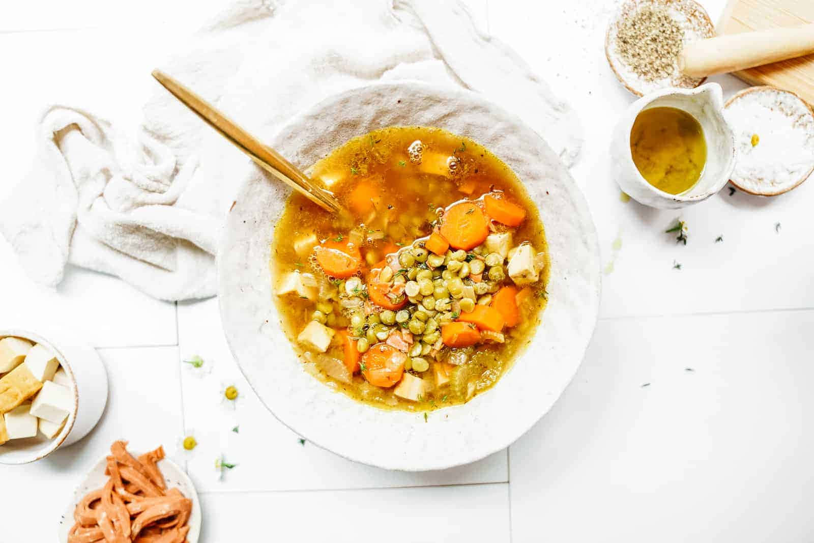 Soup 桌布 壁紙 — 一碗鄉村風味濃郁的扁豆紅蘿蔔湯配豆腐，飾以新鮮香草，置於亮白色瓷磚表面上。