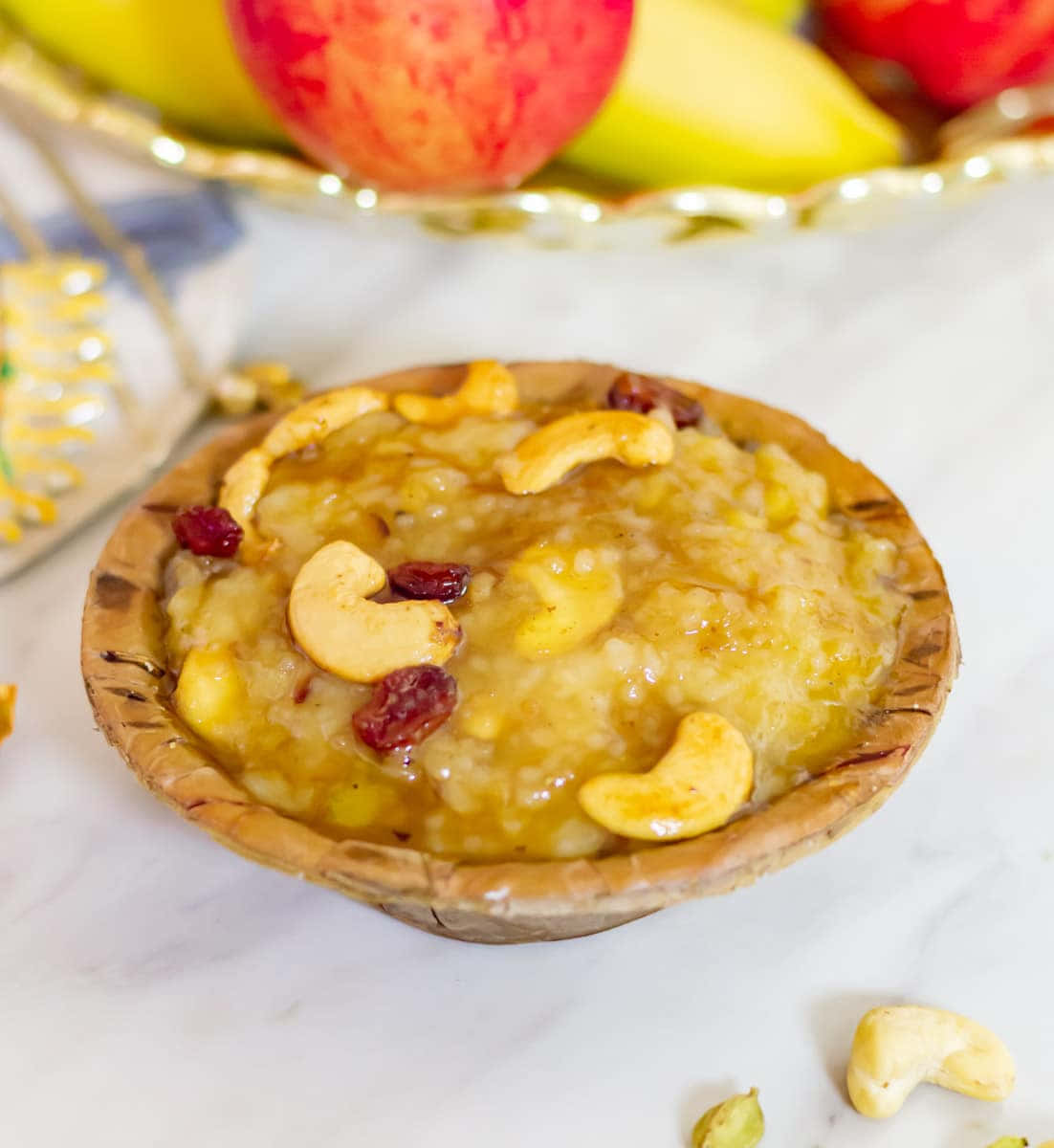 Pongal 桌布 壁紙 — 一碗鄉村風格的黃金燕麥片，上面放有腰果和蔓越莓，放在大理石表面上，背景有新鮮水果。