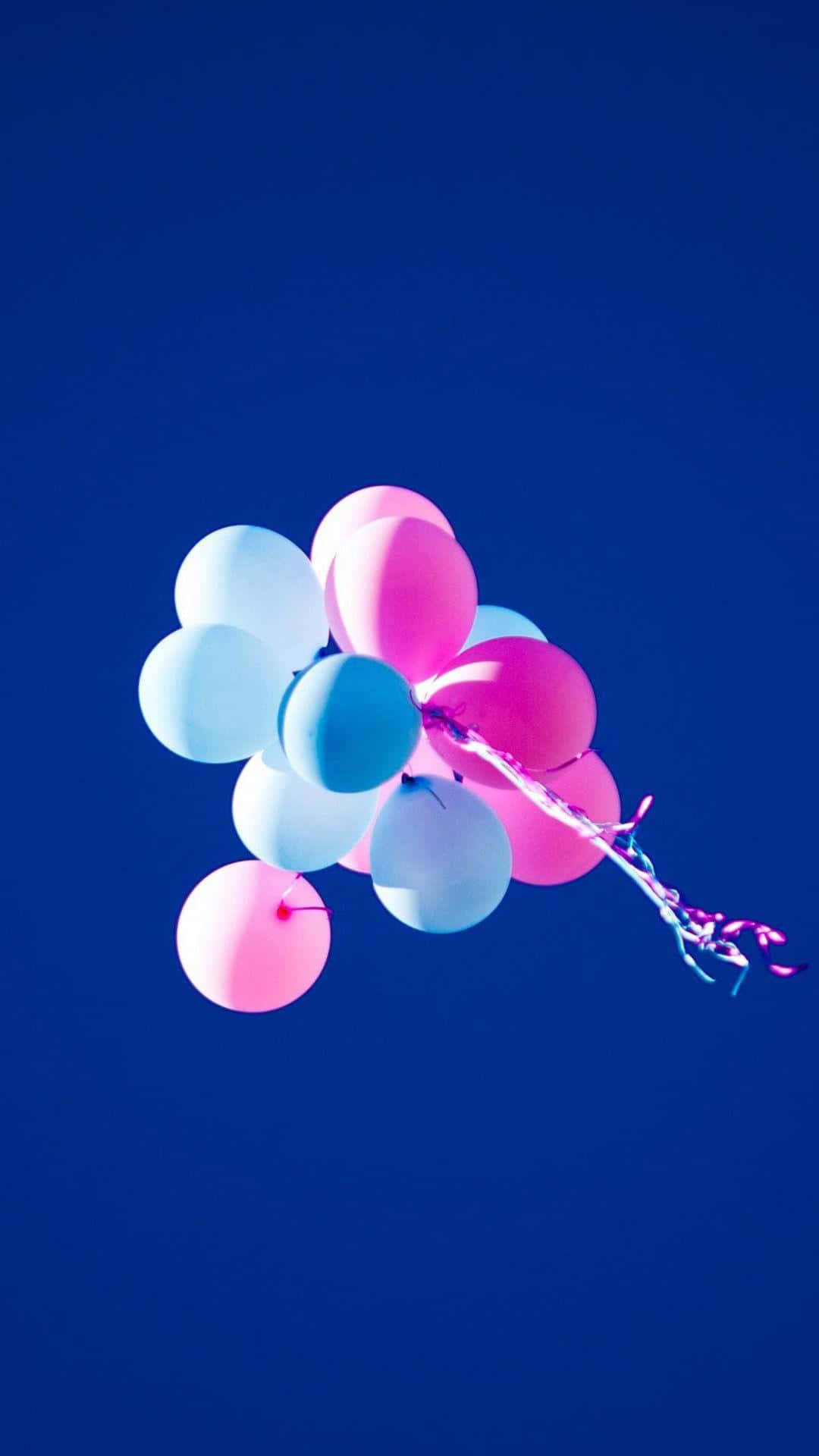 Balloon 桌布 壁紙 — 一簇粉紅色和藍色的氣球在深寶藍色的天空中飄浮，帶著一條拖曳的絲帶。